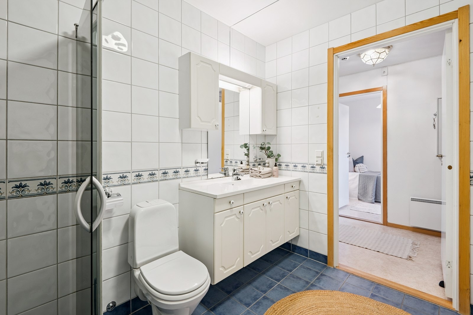 Badet er utstyrt med dusjhjørne med glassdører, servant med underskap og WC. Galleribilde