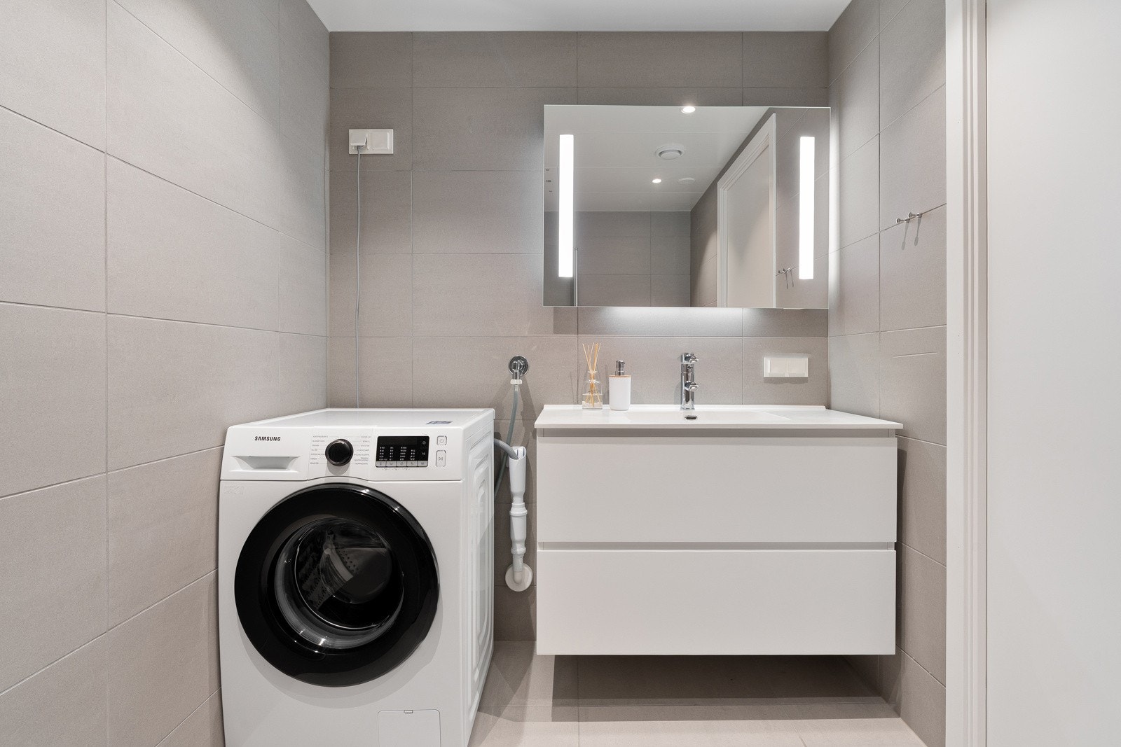 Stort dusjhjørne med innfellbare glassdører. Badet har opplegg for vaskemaskin og plass for tørketrommel.