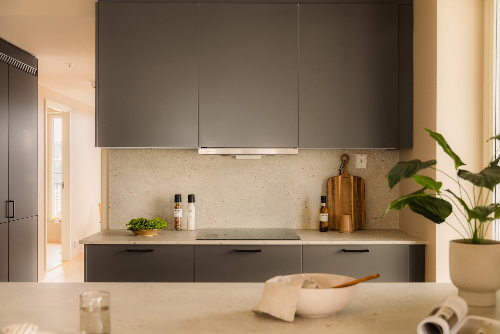 Kjøkkeninnredningen har glatte, mørke fronter kombinert med en elegant og slitesterk benkeplate som tåler daglig bruk. Galleribilde