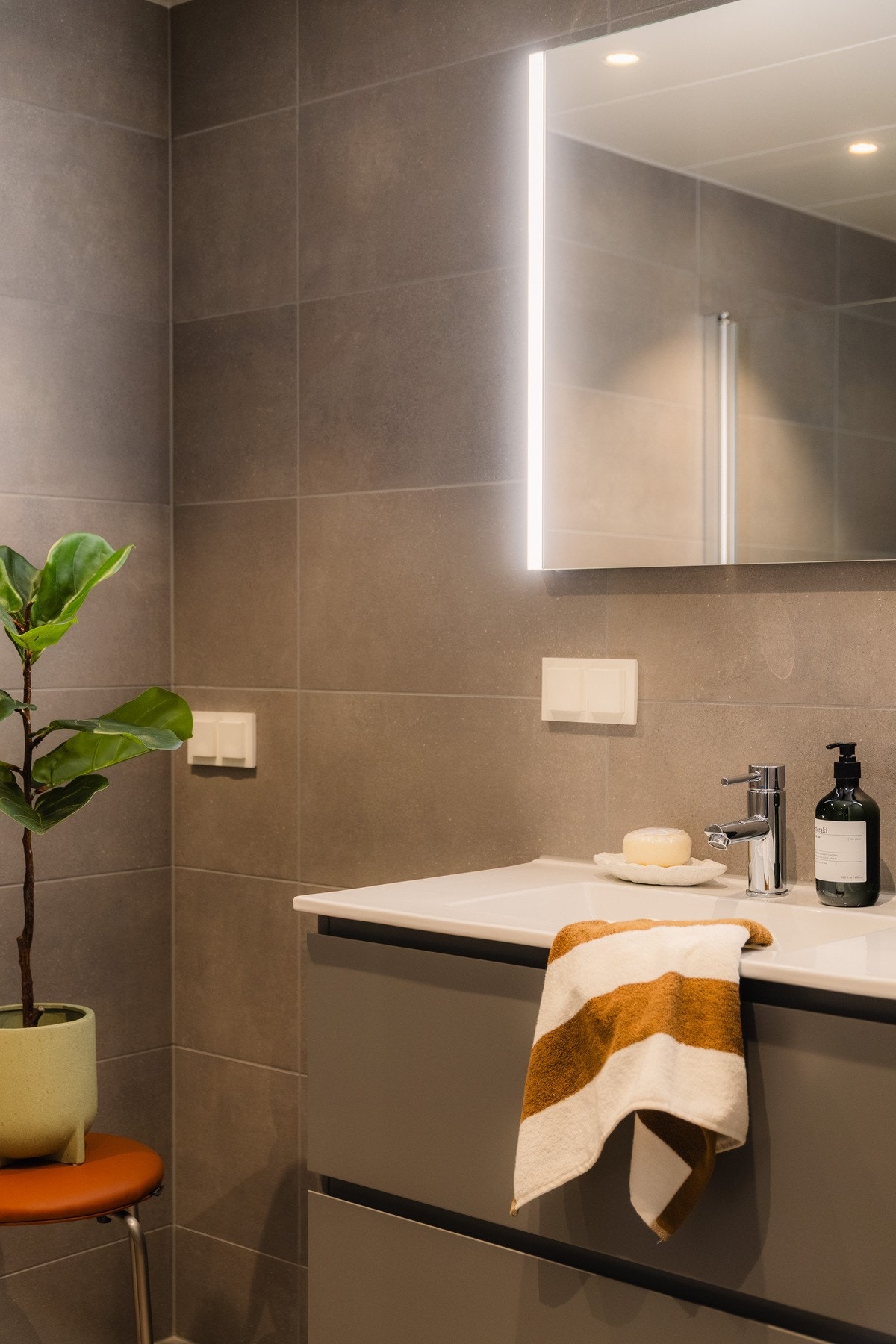 Baderommene har pene flislagte overflater og er innredet med dusjhjørne, moderne servantinnredning, speil med integrert belysning og vegghengt toalett. Galleribilde