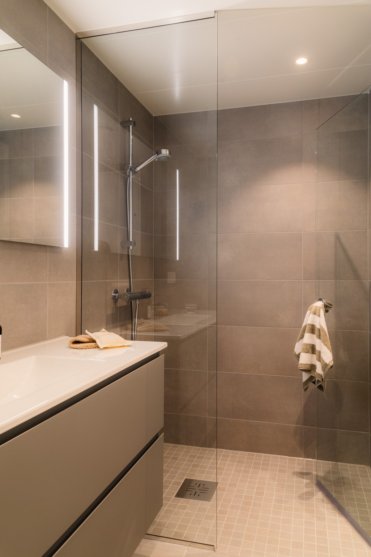 Innredet med dusjhjørne, moderne servantinnredning, speil med integrert belysning og vegghengt toalett. Galleribilde