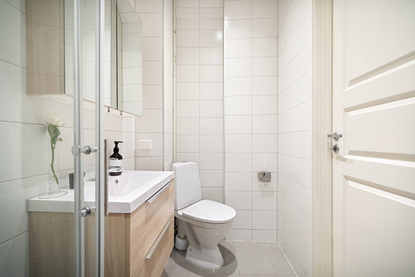 Badet inneholder gulvmontert toalett, vegghengt servantinnredning med skuffer og ovenpåliggende vask, samt dusjhjørne. Galleribilde