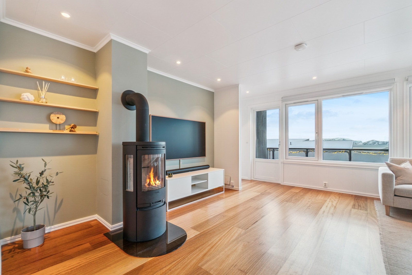 Ved vedovnen er det hengt opp hyller som gir et dekorativt og pent innslag til rommet. Galleribilde