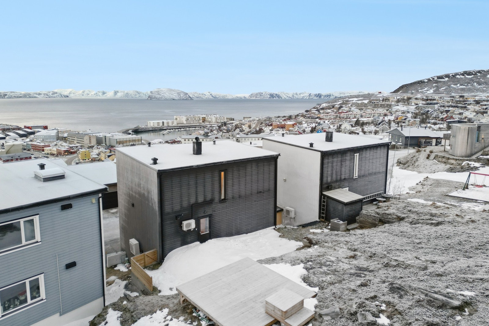 På baksiden er fjellveggen jevnet ut slik at det nå er en helning med plen. Det er støpt mur, bygget gjerde og trapp, og platt til trampoline. Galleribilde