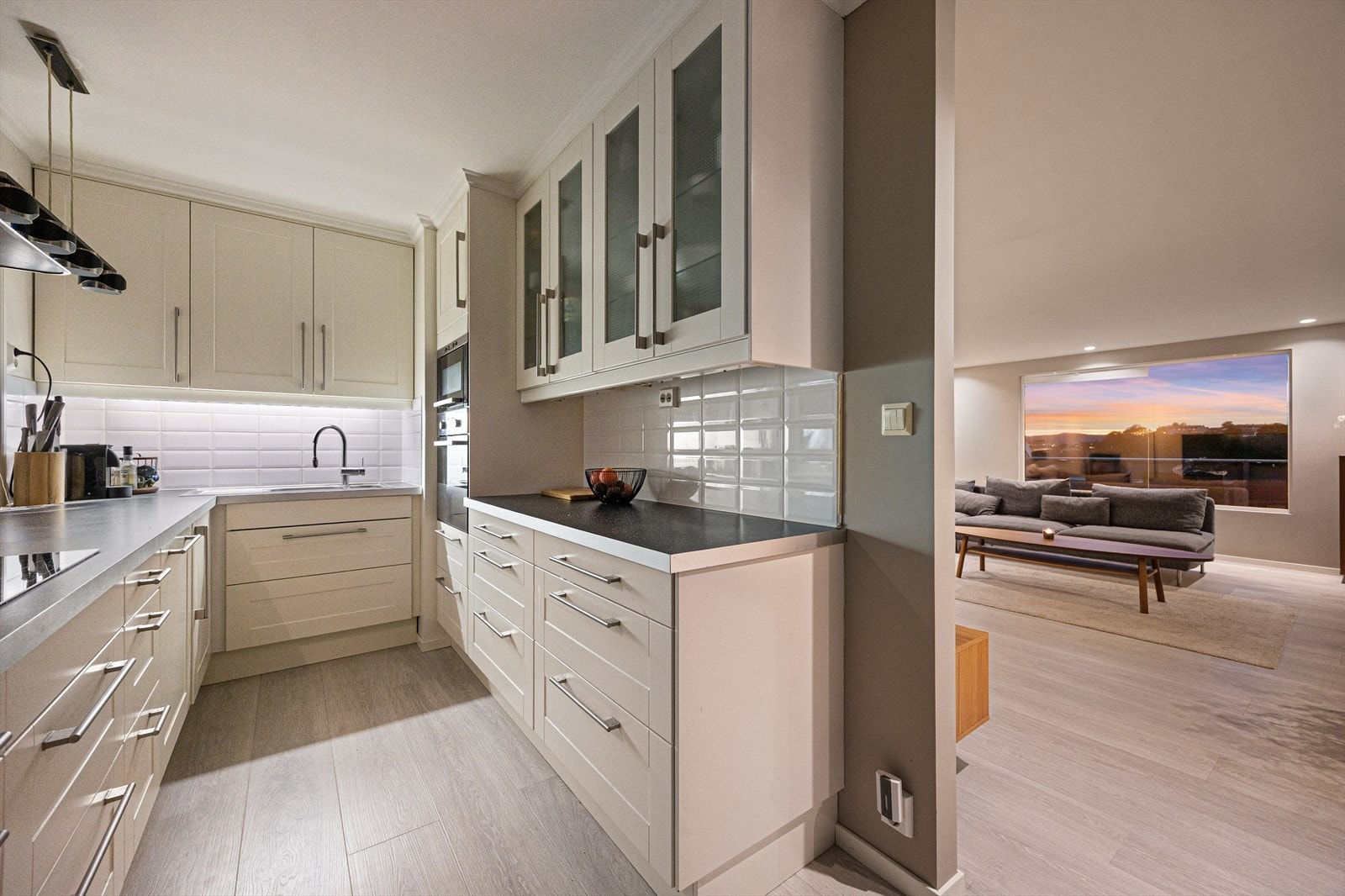 Pent og tidløst kjøkken med innredning bestående av lyse profilerte fronter og laminert benkeplate. Galleribilde