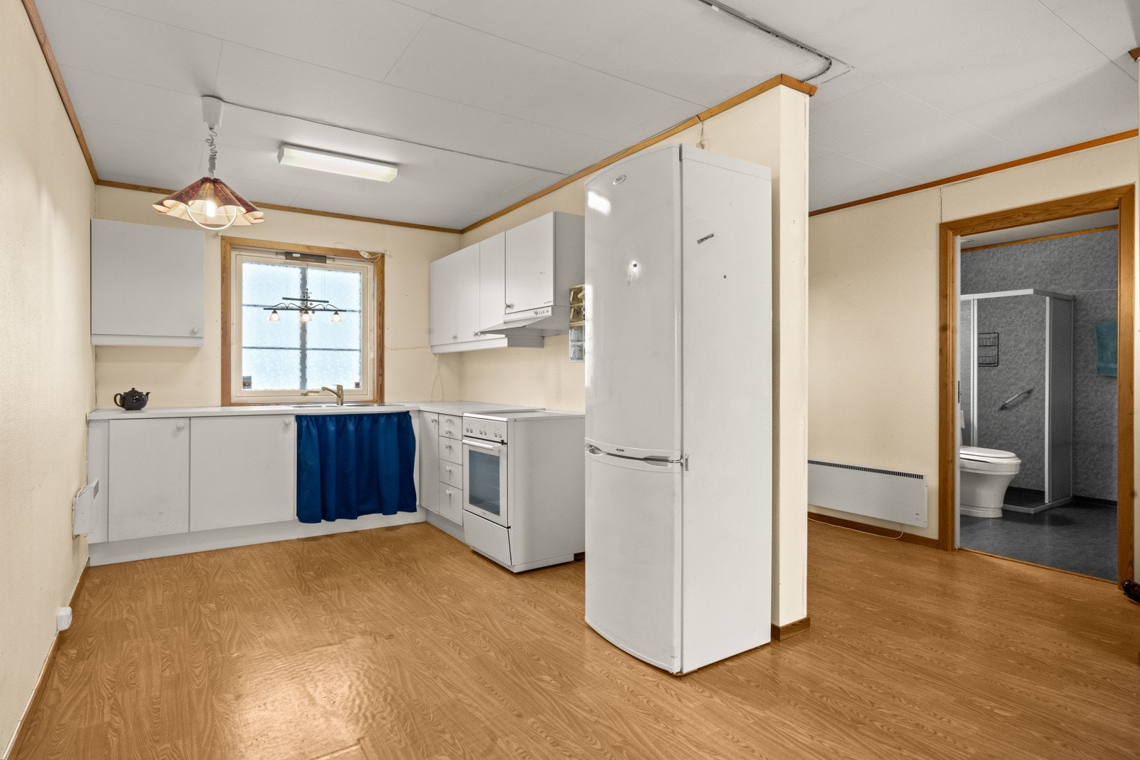 Kjøkken fra byggeår med inredning med slette fronter, benkeplate av laminat, varmtvannsbereder fra 2023 og komfyr, kjøl-/fryseskap. Galleribilde