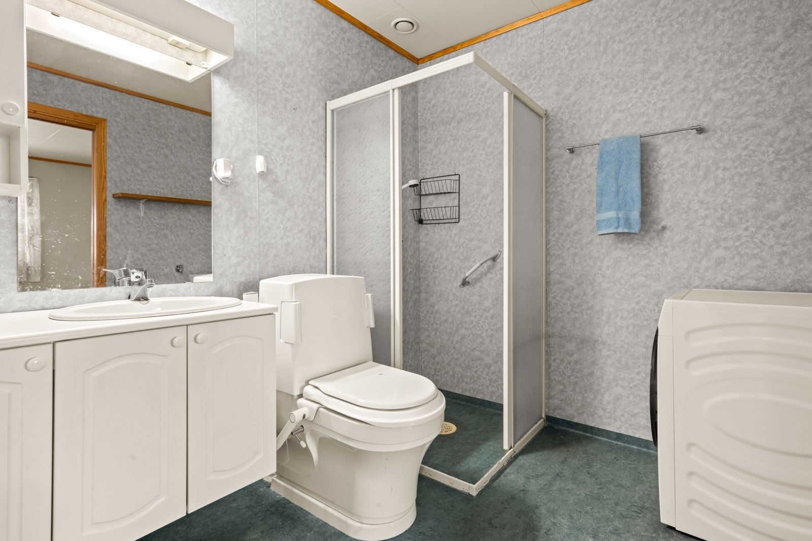 Badet er utstyrt med vegghengt servantinnredning med profilerte fronter, speil, gulvstående toalett og dusjhjørne. Galleribilde