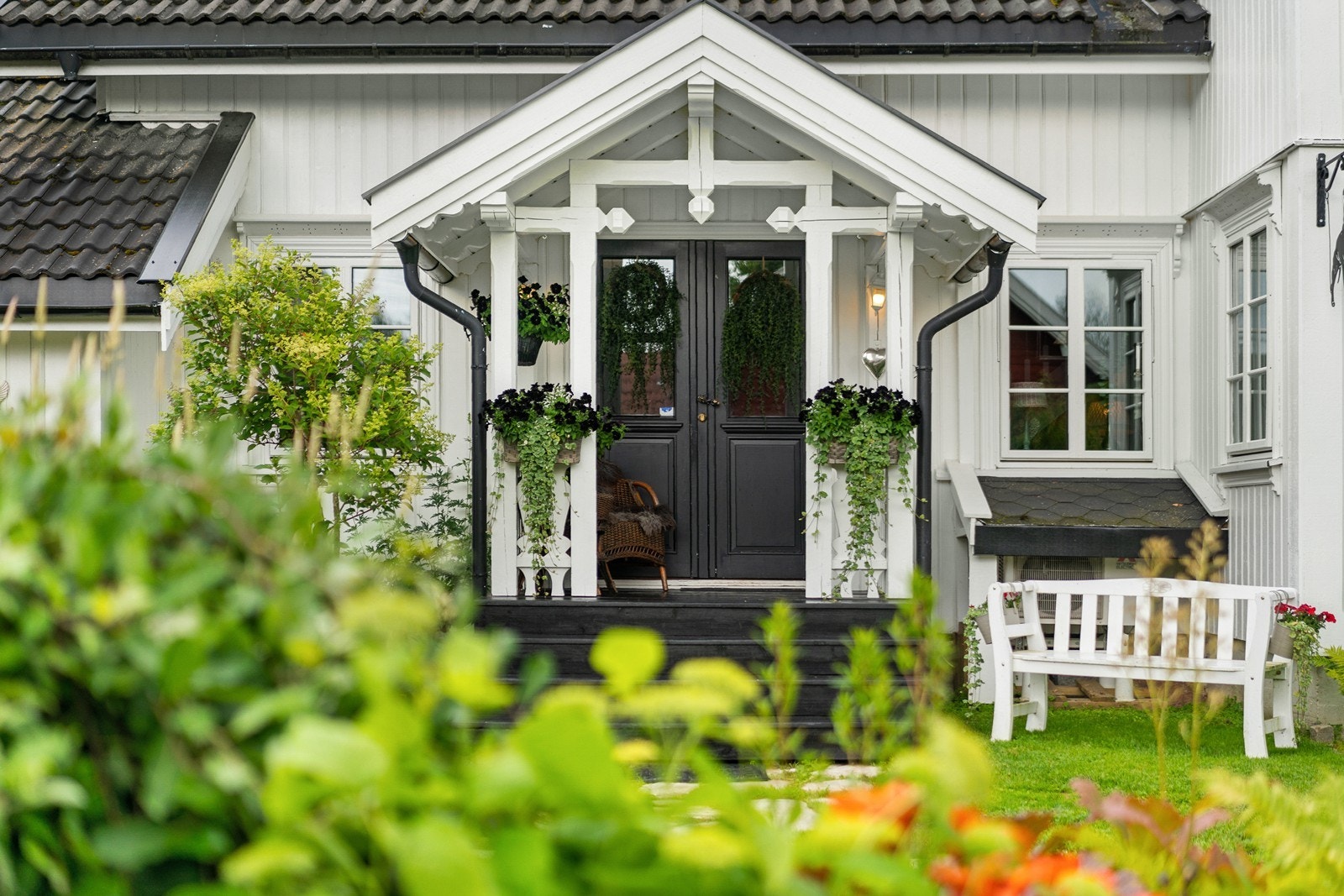 Overbygd inngangsparti med en tofløyet dør i sort utførelse. Galleribilde