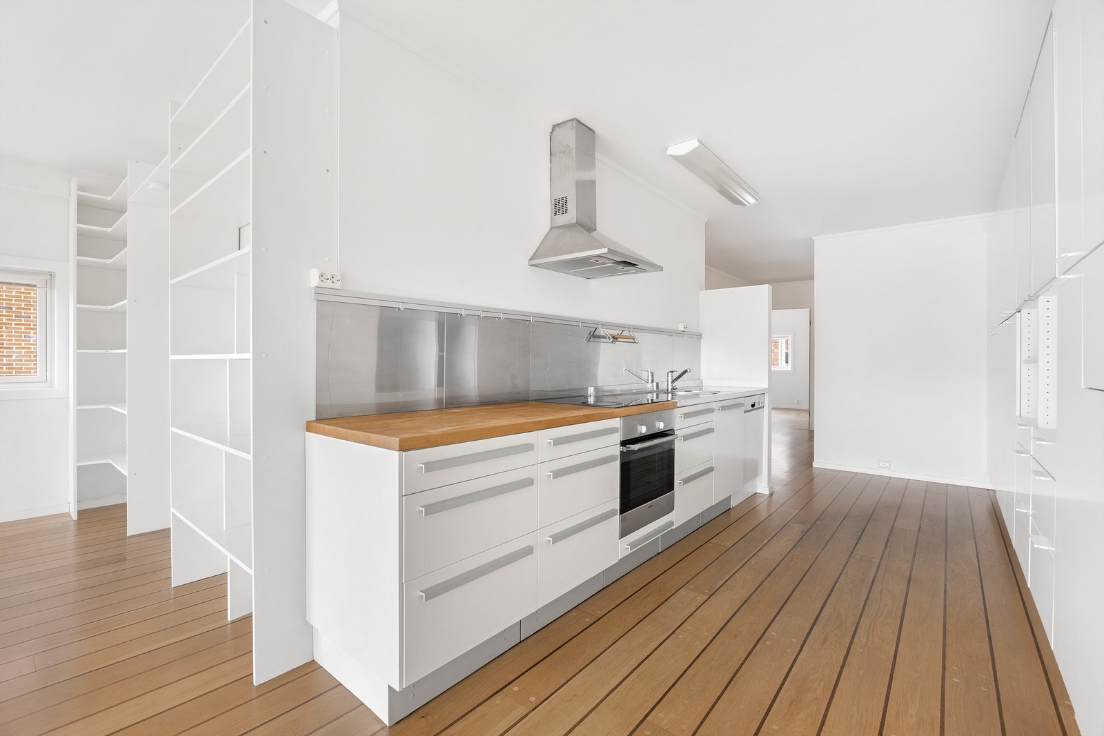 Kjøkkenet fungerer som gjennomgangsrom og er innredet med moderne, glatte fronter Galleribilde