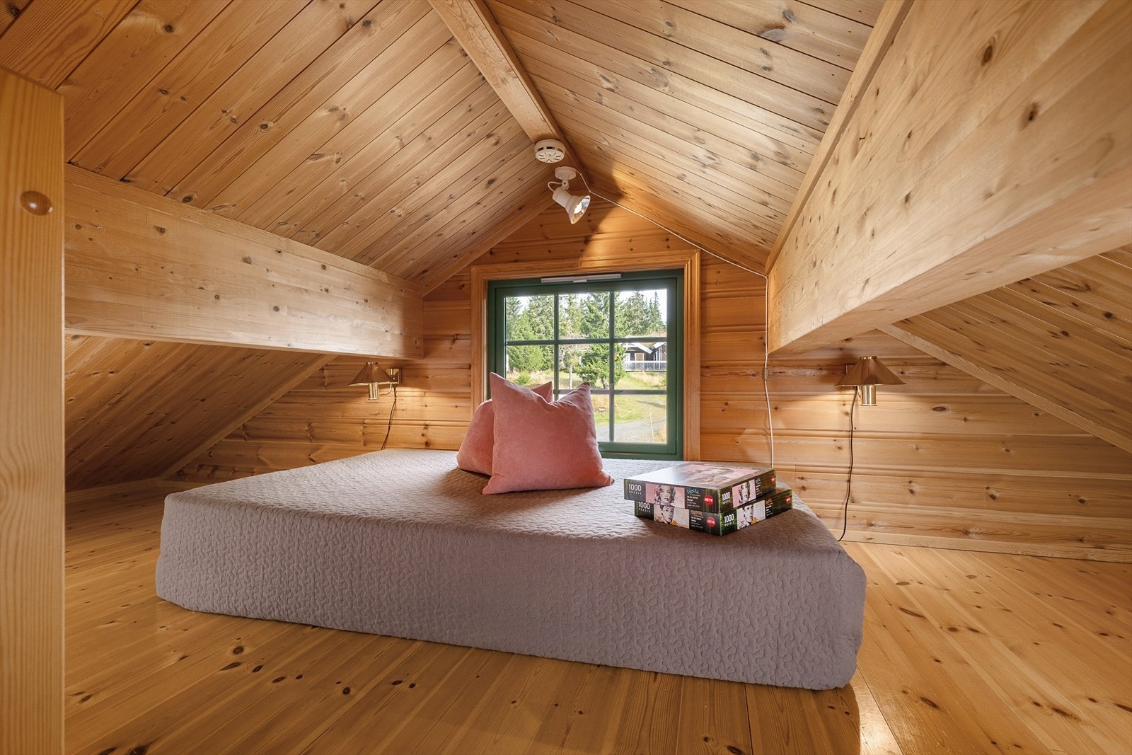Hems med plass til madrass for gjester eller en ekstra oppholdsplass når en er mange på hytta. Vinduet på hemsen slipper inn fint lys. Galleribilde