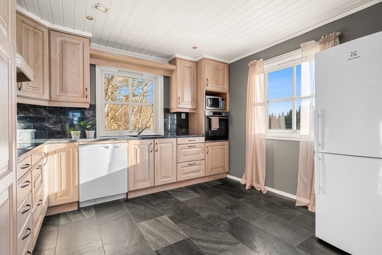 Kjøkkenet er romslige 12 m² og har plass til en liten spisebordsløsning. Store vindusflater slipper inn godt med naturlig lys og skaper en lys og trivelig atmosfære. Galleribilde