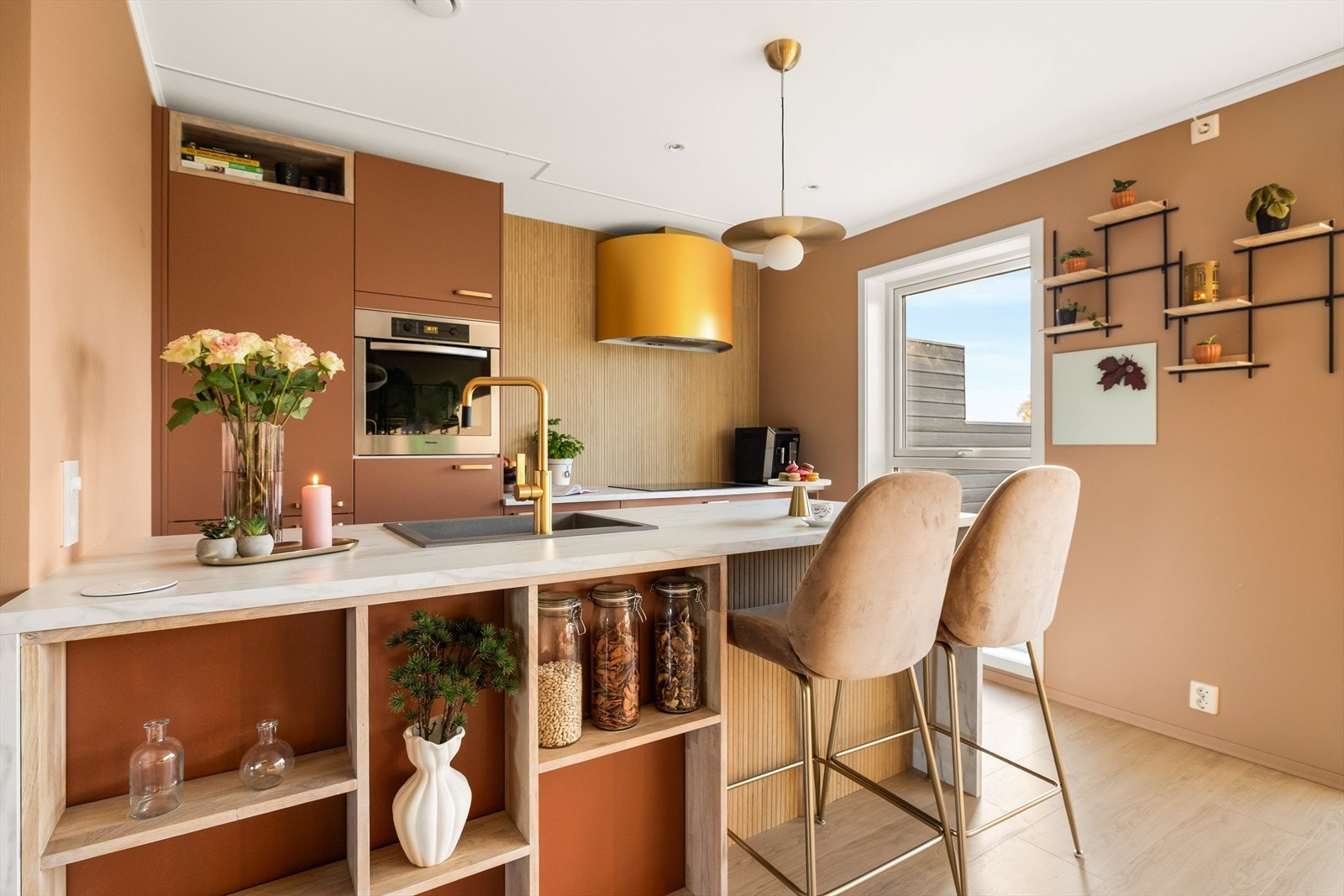 Kjøkkenøy med vask, messingfarget blandebatteri og sitteplass for to. Galleribilde