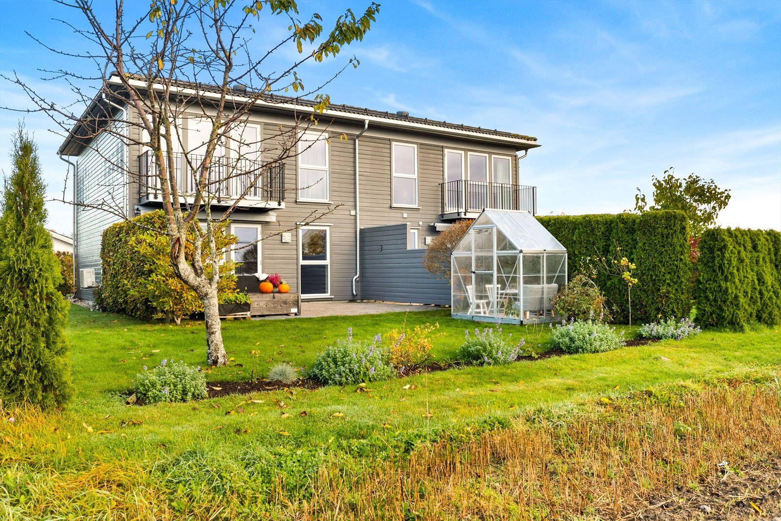 På baksiden av huset er det en pent avskjermet hage med drivhus. Galleribilde