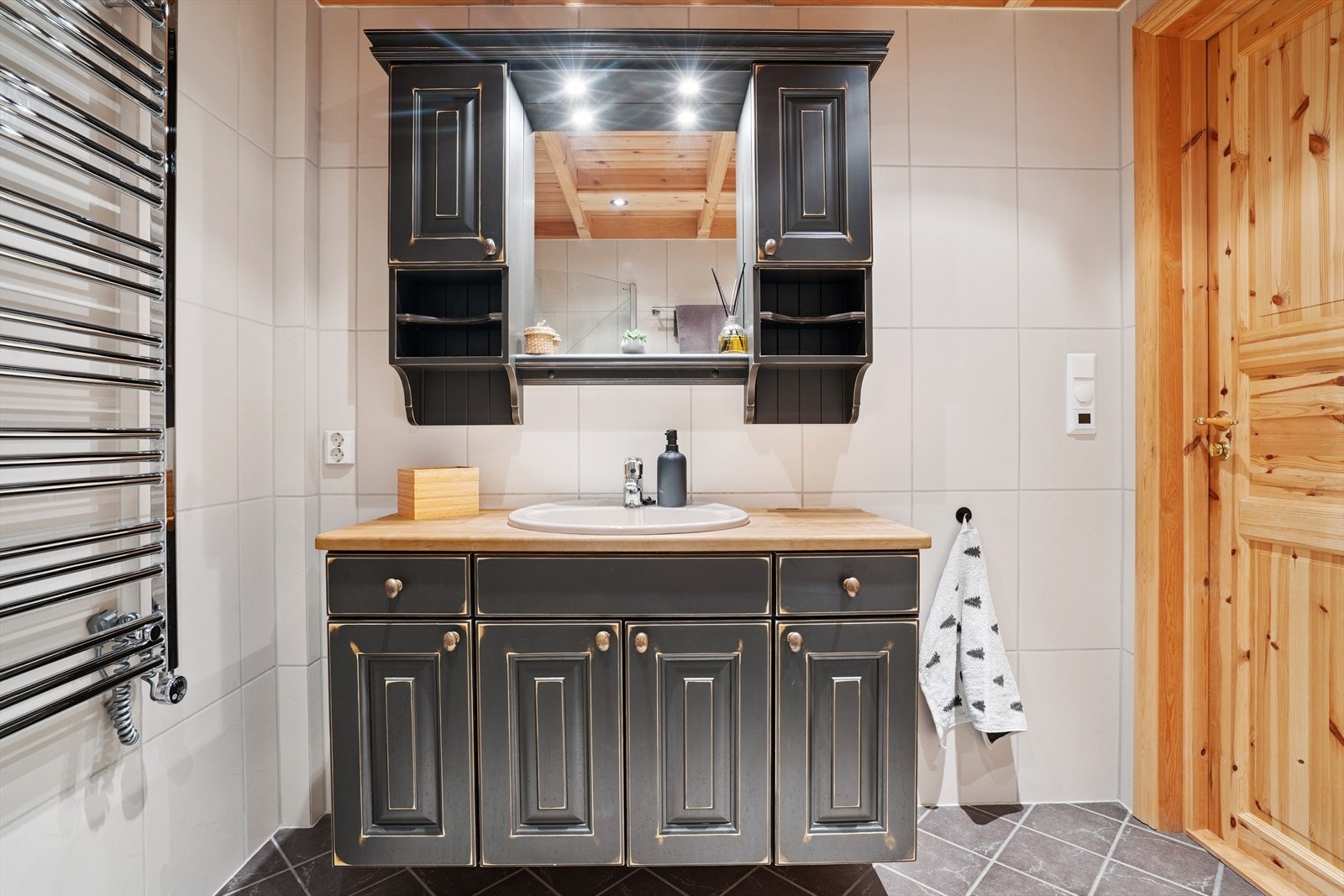 Videre er det servant i heltre baderomsinnredning, samt overskap og speil med lys. Galleribilde