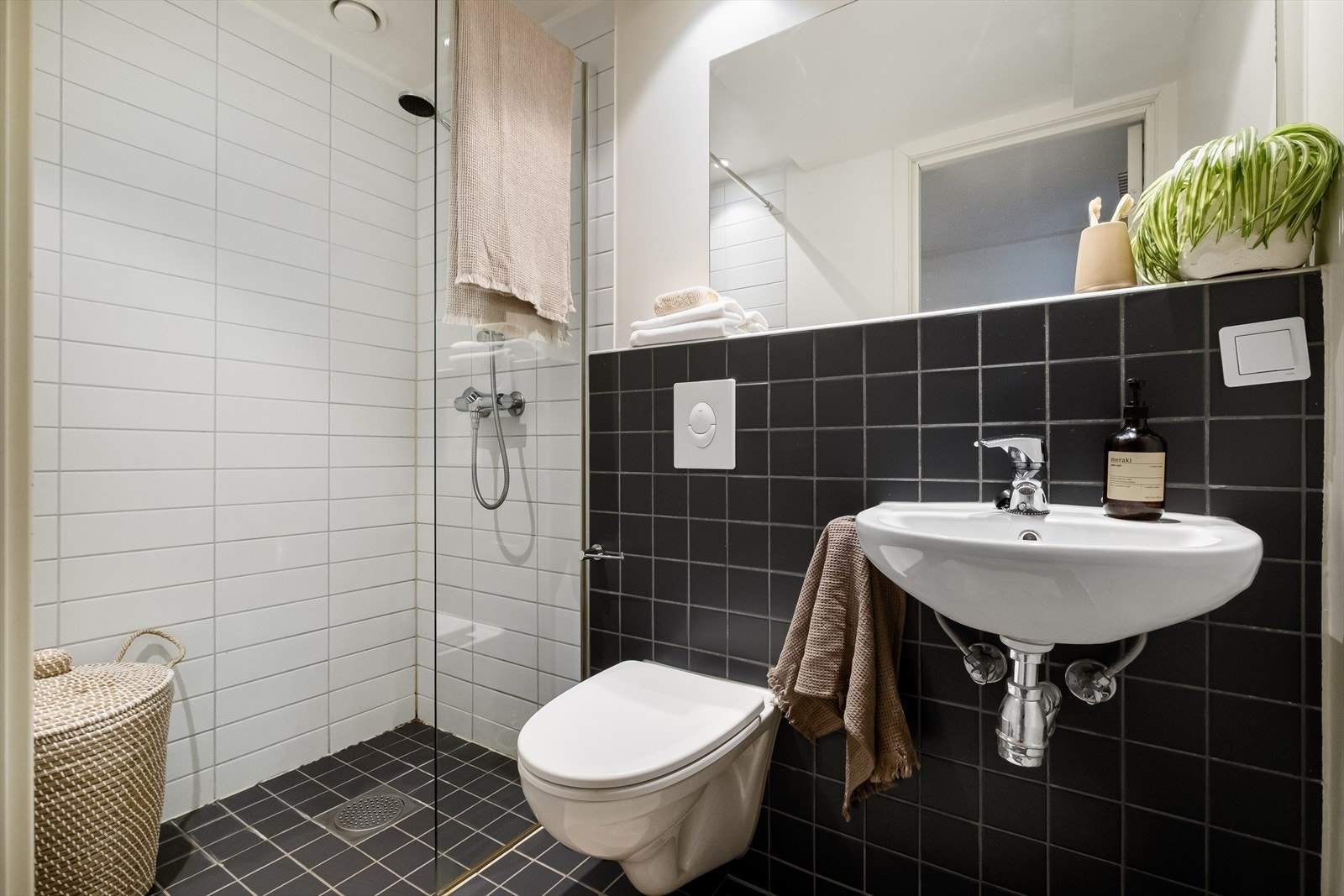 Baderom med flislagt gulv, varmekabler, fliser og malte flater på vegger, avtrekk, speil, downlights, servant dusj hjørne med glassvegg, vegghengt toalett. Galleribilde