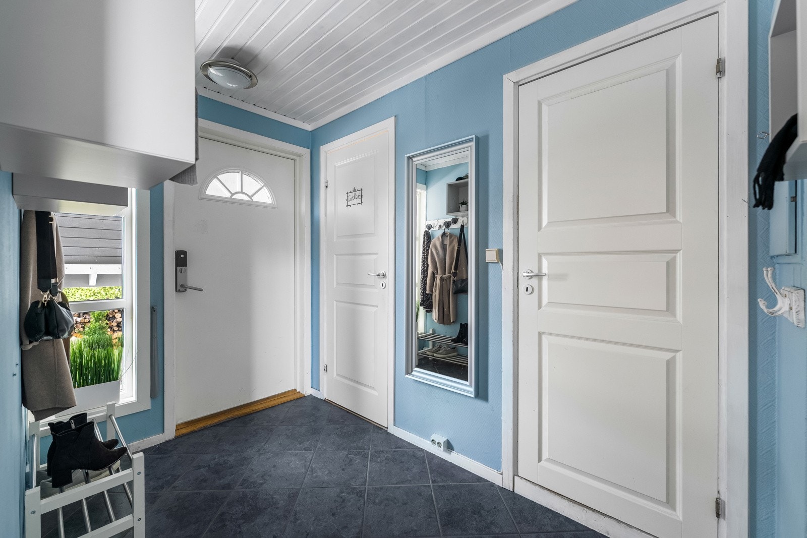 Inngang. Isolert ytterdør med glassfelt, produsert i 2011. Dør til tolaett midt i bildet. Dør til vaskerom til høyre. Galleribilde