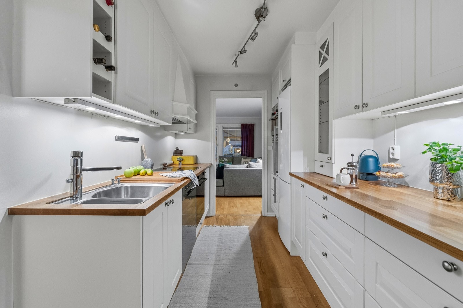 Velutstyrt og funksjonelt kjøkken med praktisk utforming på begge sider, gode arbeidsflater og rikelig med oppbevaring. Integrerte hvitevarer: platetopp, stekeovn oppvaskmaskin og mikrobølgeovn. Det er god plass til kombinert frittstående kjøleskap/frys Galleribilde