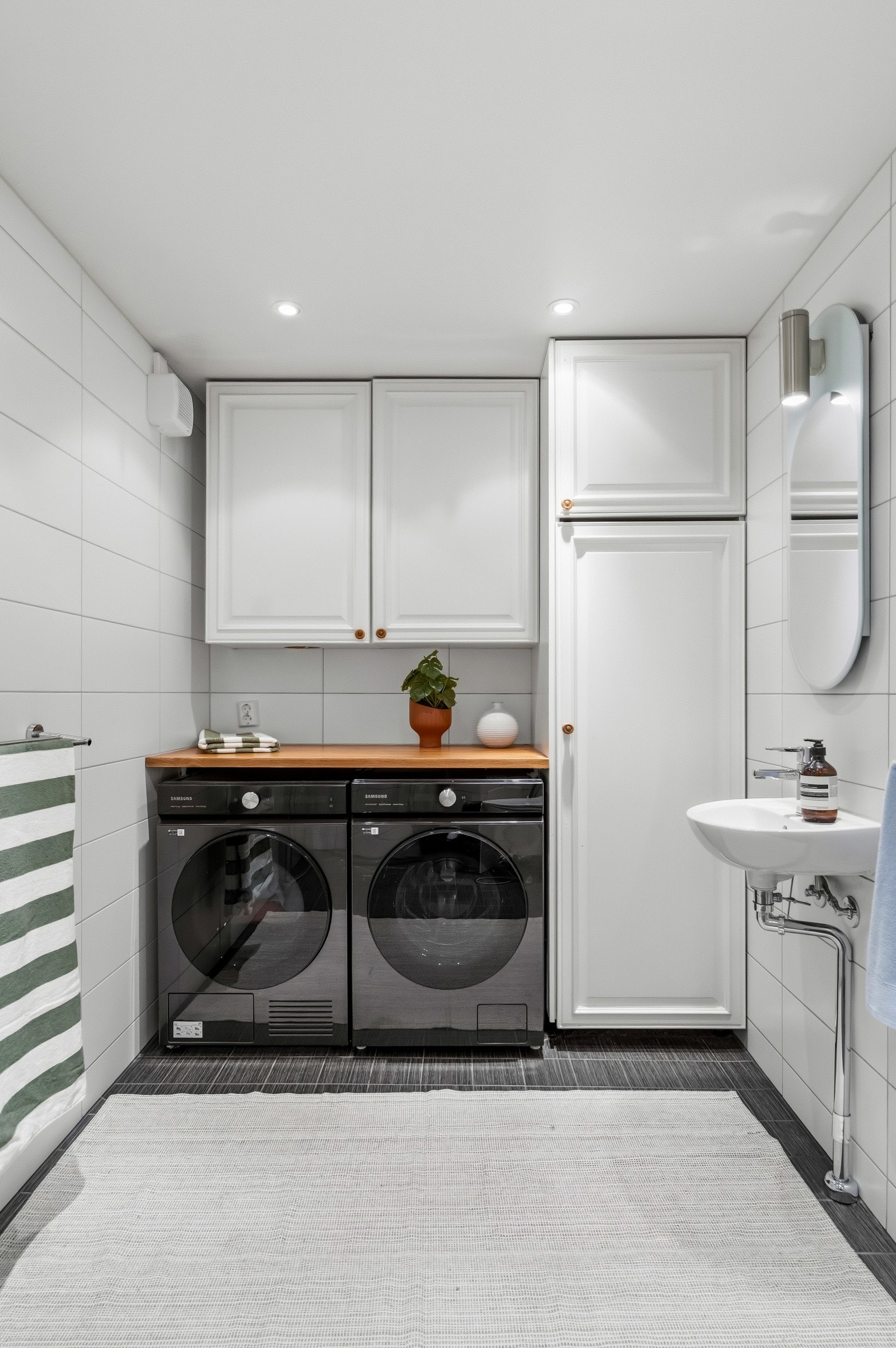 Badet har dusjdører i glass, vegghengt toalett, downlights og opplegg for vaskemaskin / tørketrommel. Galleribilde