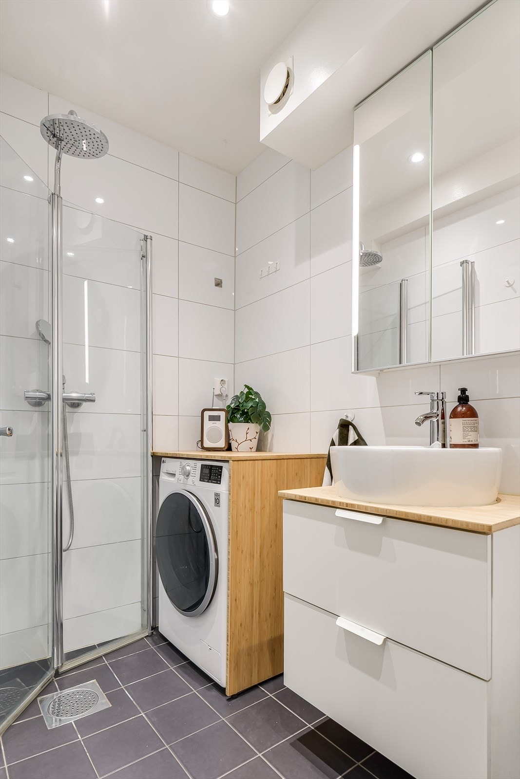 Badet er utstyrt med et veggmontert toalett, en servantinnredning et dusjhjørne med foldbare glassdører, samt opplegg for vaskemaskin. Vaskemaskin kan følge leiligheten om ønskelig. Galleribilde