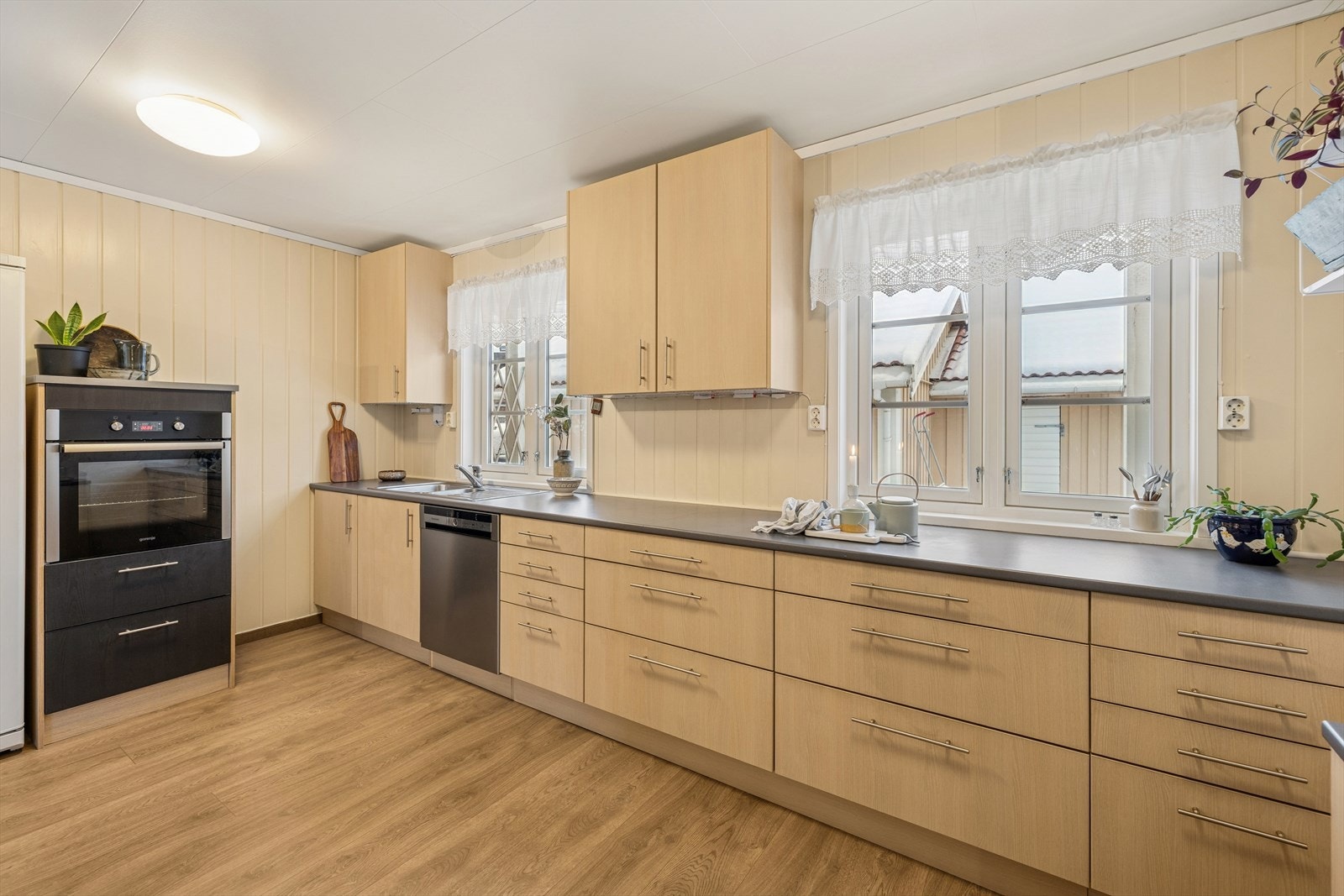 Kjøkkenet har en pen innredning med brune, glatte fronter og laminert benkeplate med nedfelt dobbel kjøkkenkum. Galleribilde