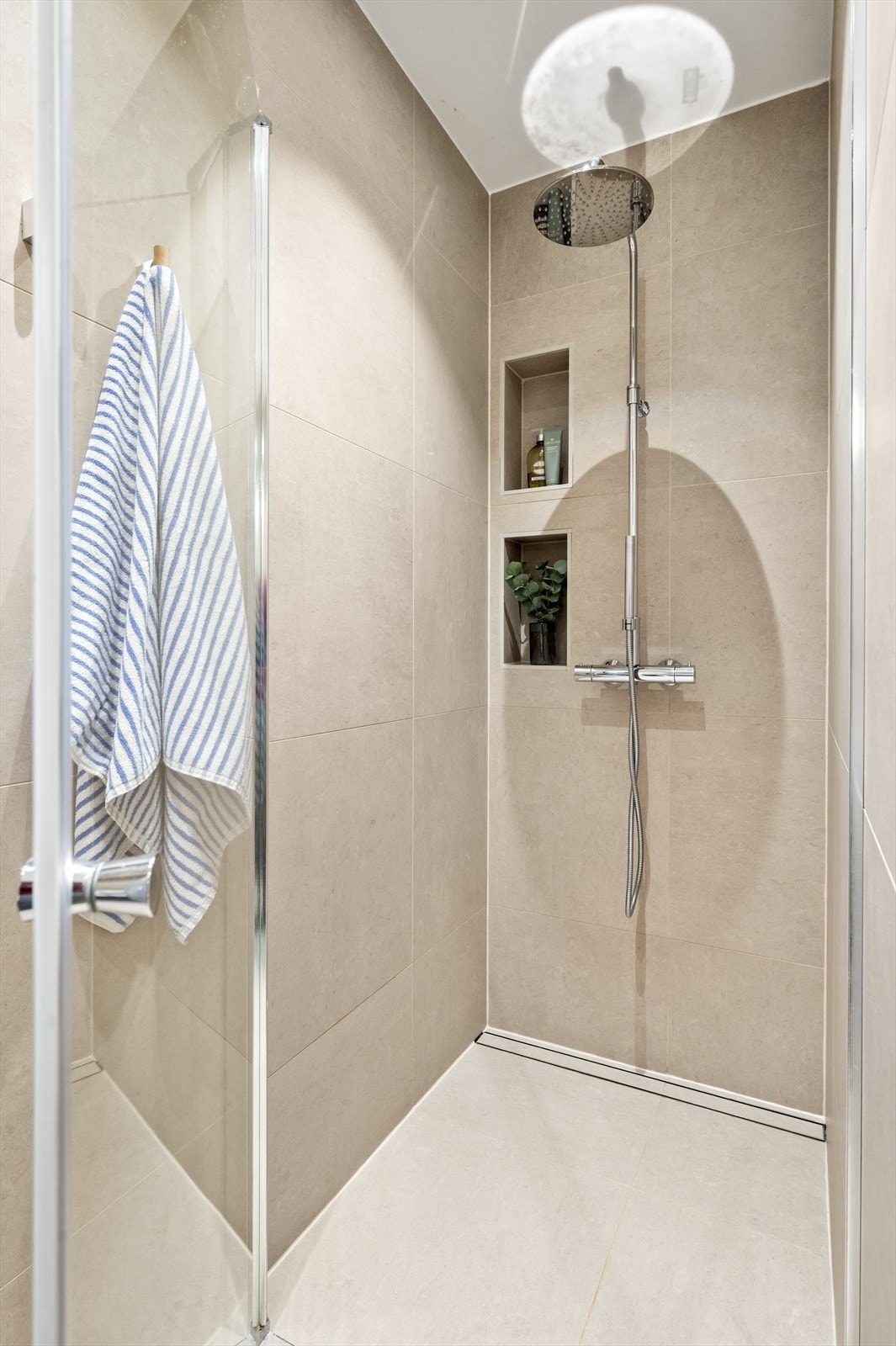 Dusjhjørnet har svingbare glassdører og praktiske, innebygde hyller for oppbevaring. Galleribilde