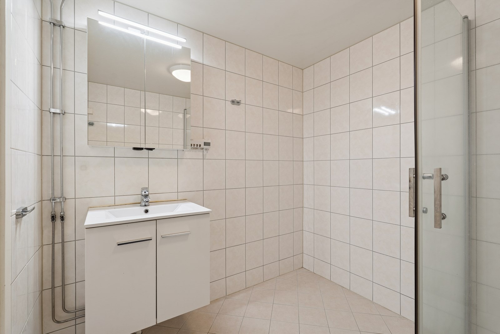 Badet er utstyrt med dusjhjørne, opplegg for vaskemaskin og en moderne baderomsinnrending. Galleribilde