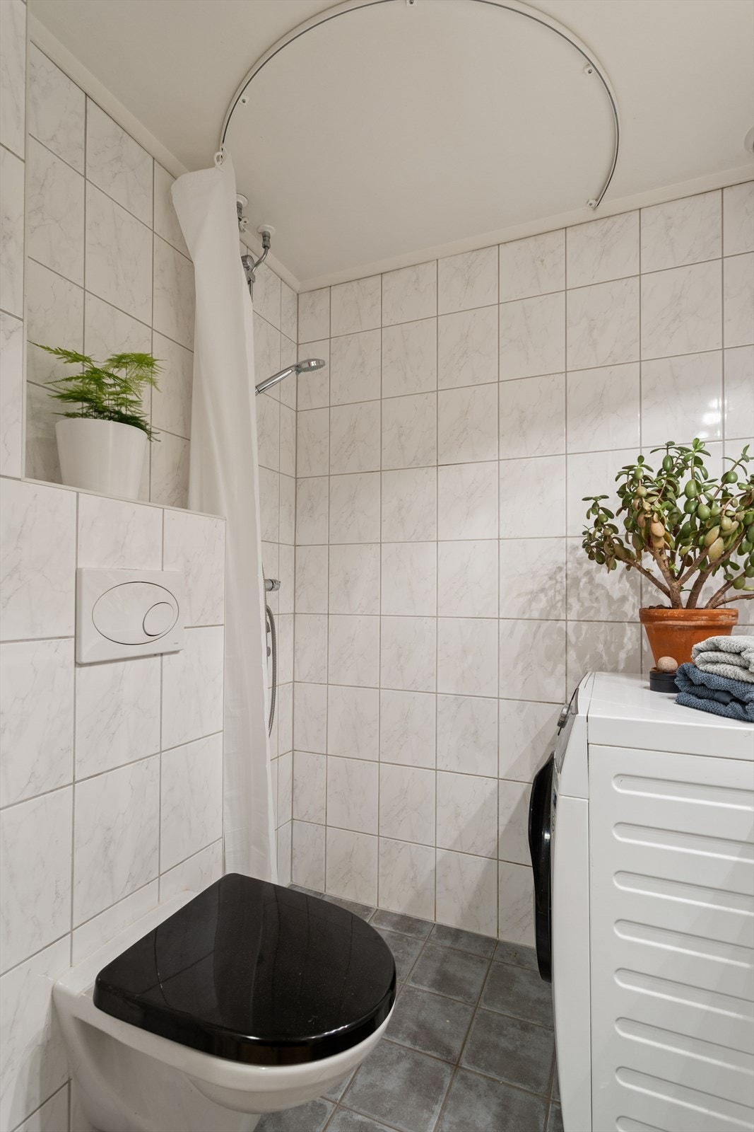 Badet består av vegghengt wc, servant m/underskap, overskap m/speilfronter og overlys, åpen dusj m/forheng og opplegg for vaskemaskin. Galleribilde