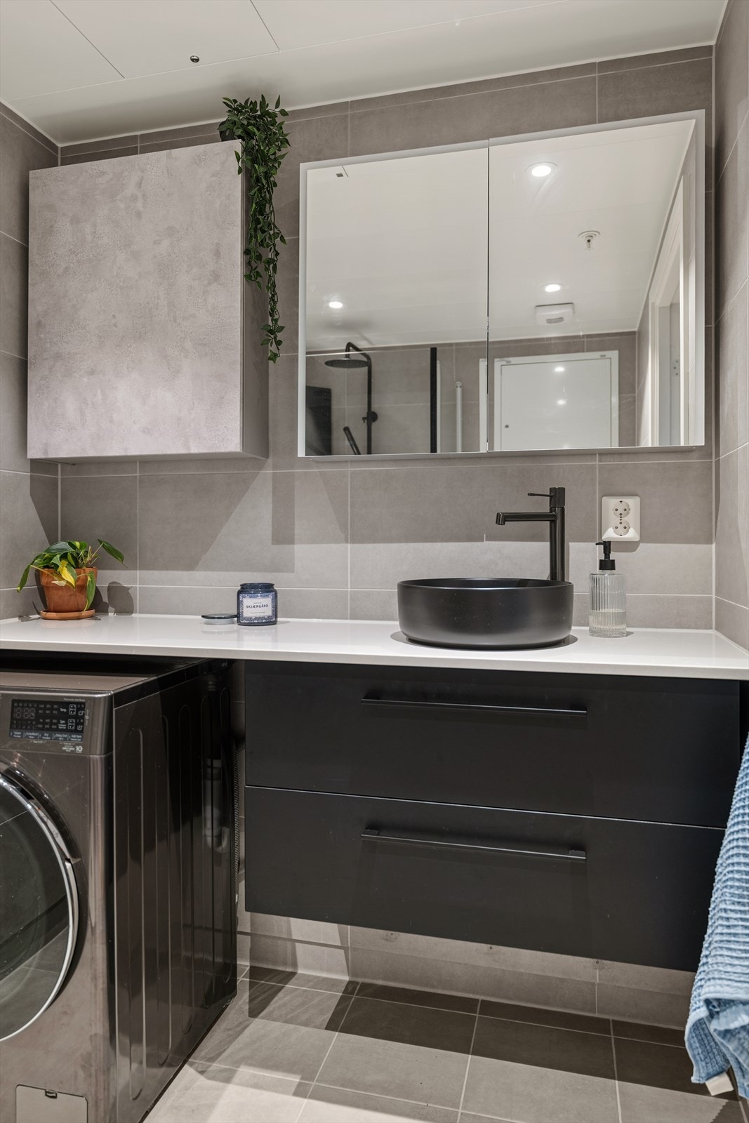 Badet er utstyrt med heldekkende servant, skuffer under benken og overskap med speilfronter gir rikelig med oppbevaring Galleribilde