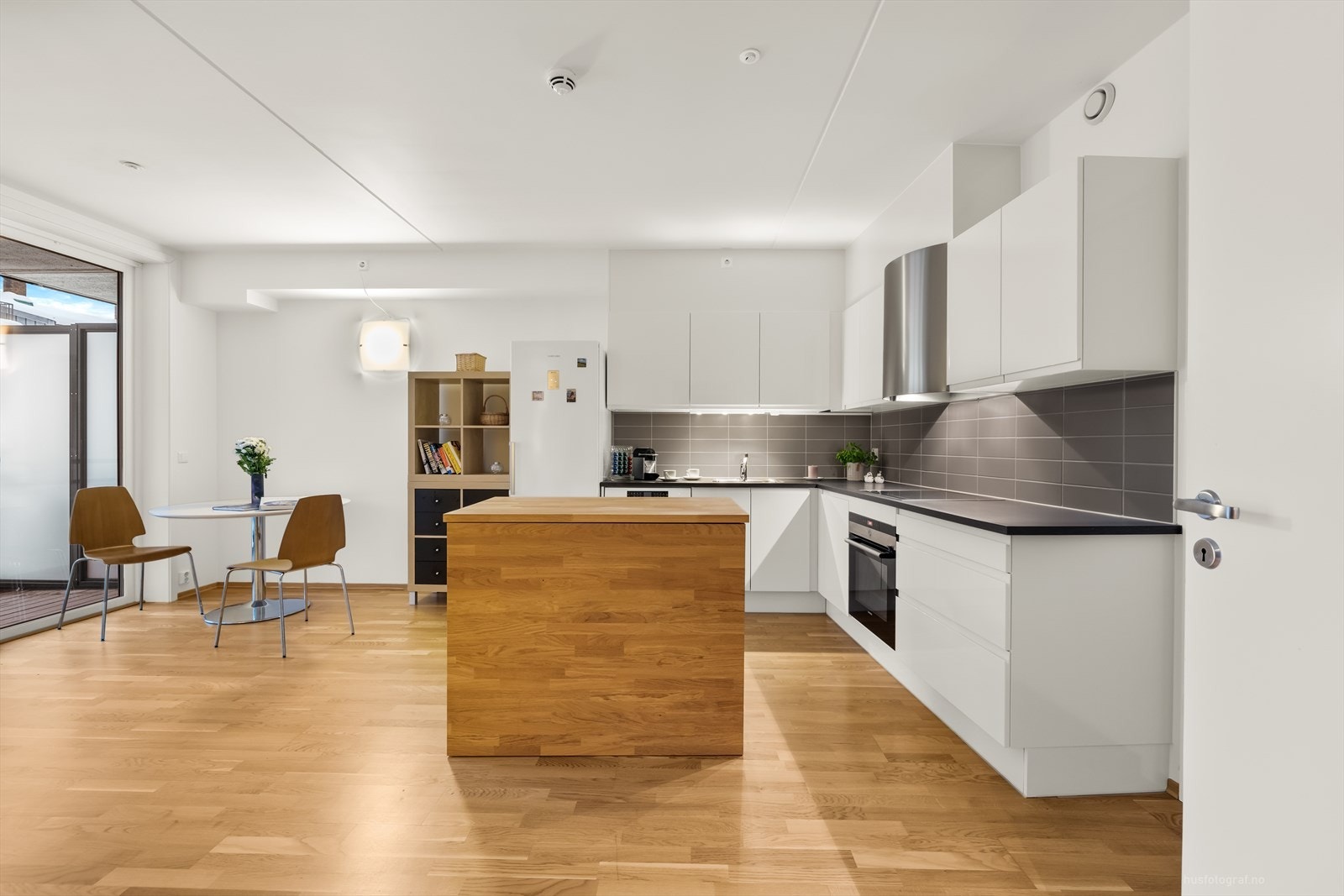 Pen kjøkkeninnredning med overflater som består av hvite glatte fronter og benkeplate av laminat. Galleribilde