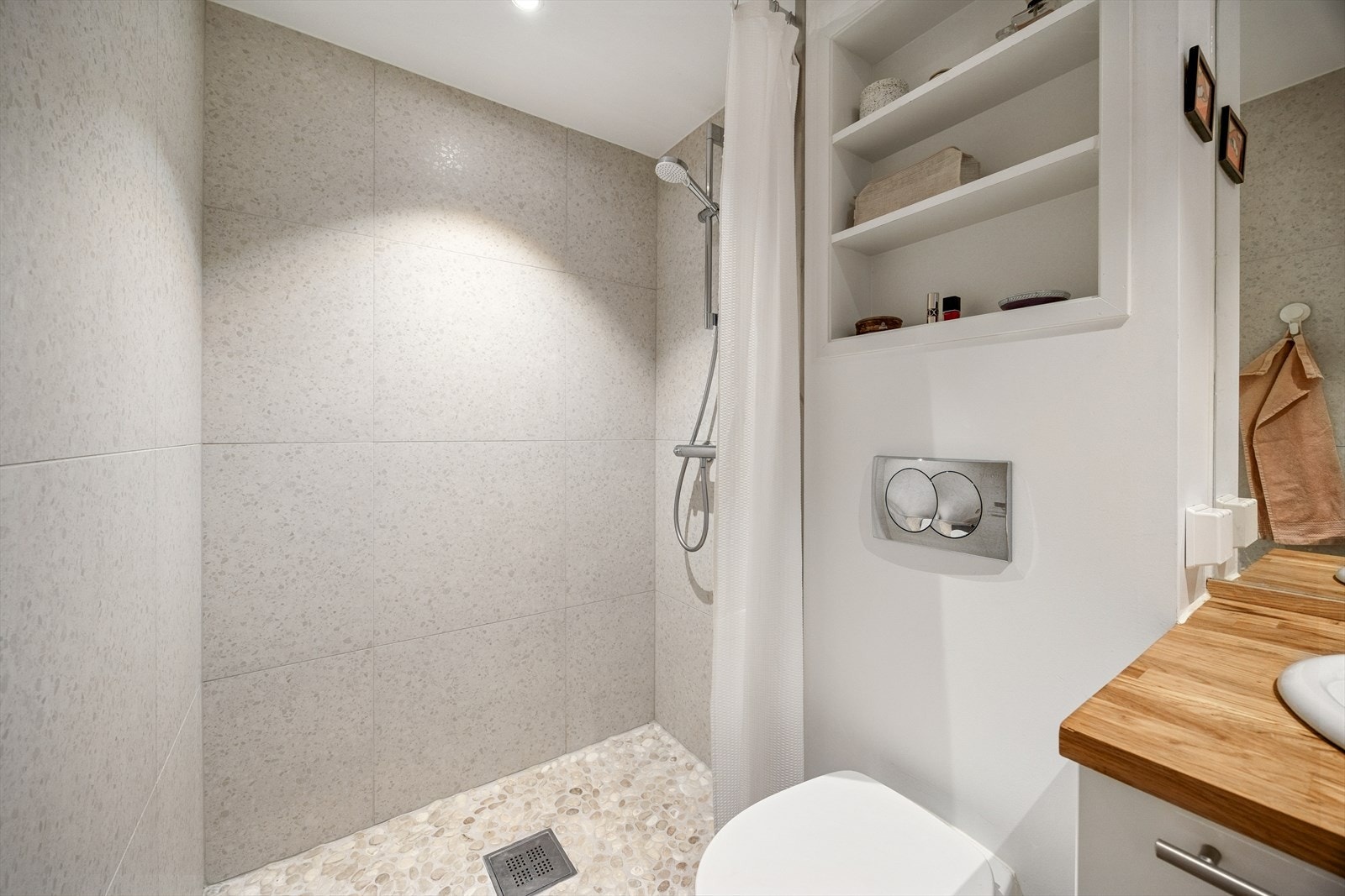 Badet er utstyrt med vegghengt toalett, dusjhjørne og servant med skapplass. Galleribilde