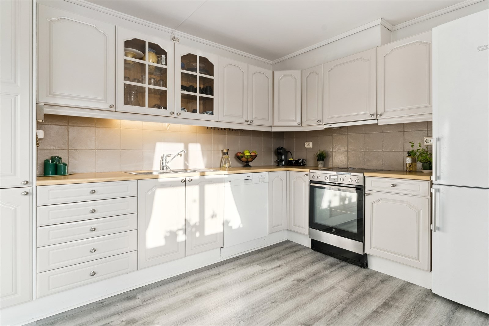 Lyst og pent kjøkken med profilerte frontar og eit klassisk uttrykk. Kjøkkenet har god skap- og benkeplass med fliser mellom under- og overskap. Galleribilde