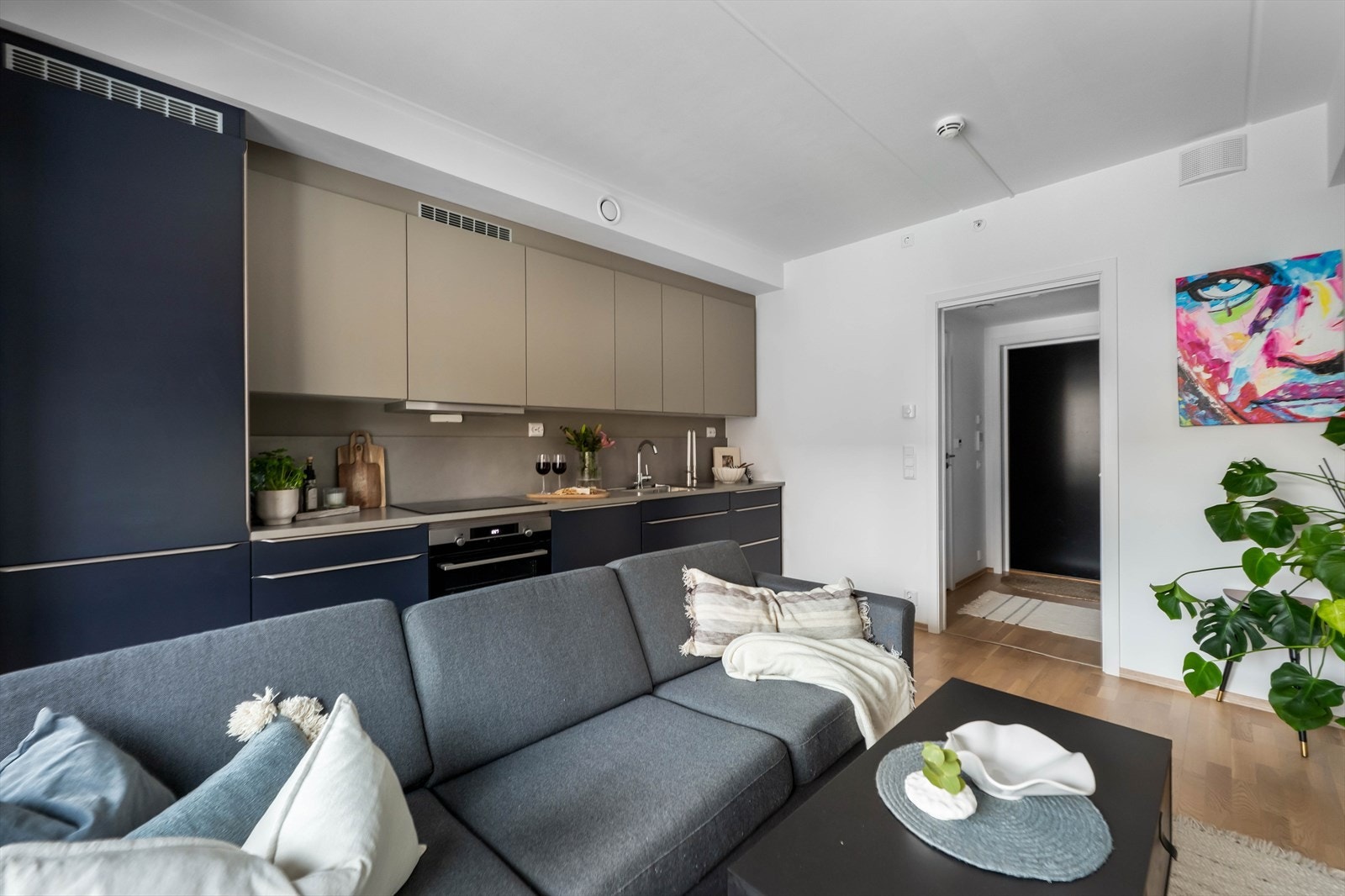 Kombinasjonen av parkettgulv og glatte kjøkkenfronter skaper en helhetlig og elegant interiørløsning med et moderne preg. Galleribilde