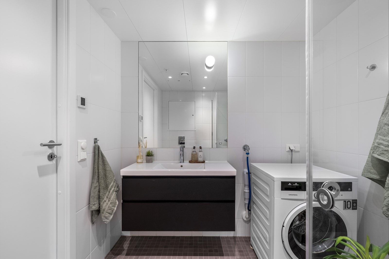Baderomsinnredning med heldekkende servant og opplegg for vaskemaskin gir praktisk funksjonalitet. Galleribilde