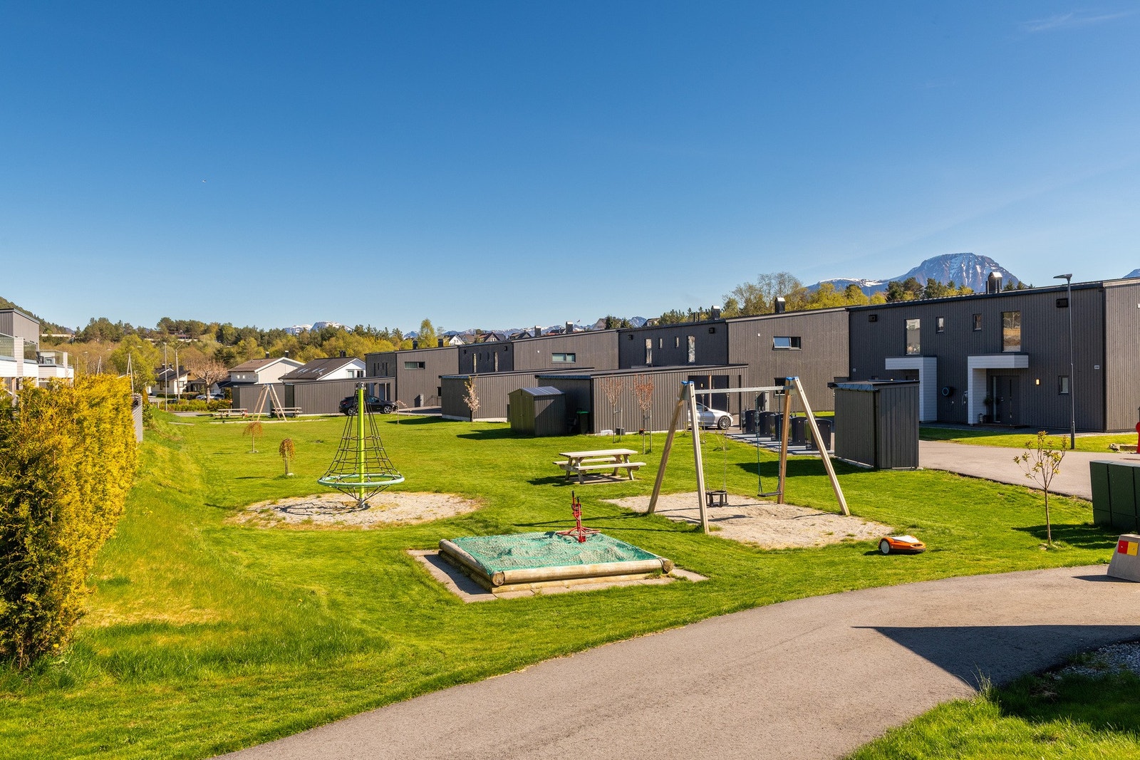 Meget flott opparbeidet fellesareal for sameiet med lekeplass, og her sørger robotklipperen for en velstelt plen. Galleribilde