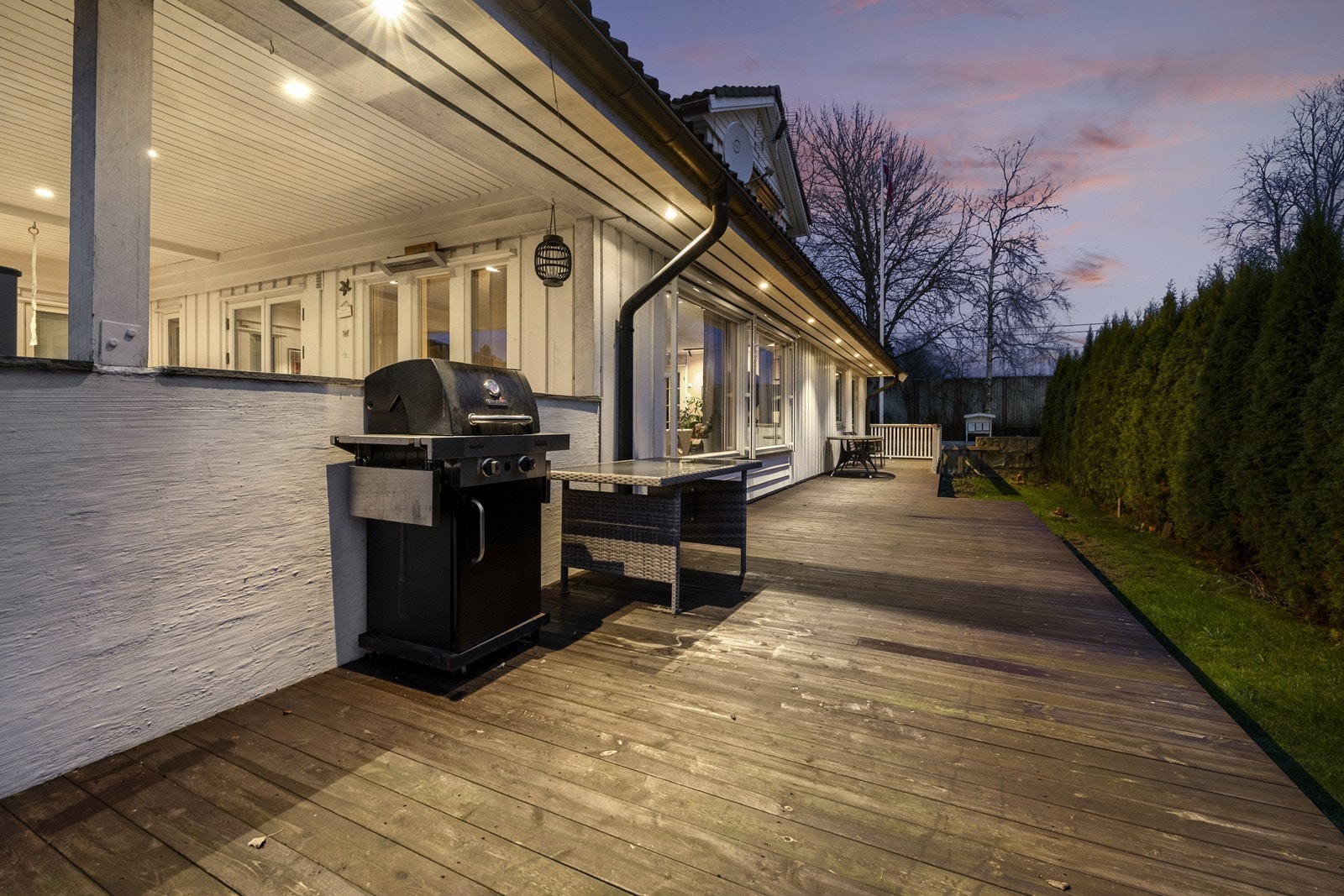 Stor og solrik terrasse som strekker seg rundt to av husets fire vegger. Galleribilde