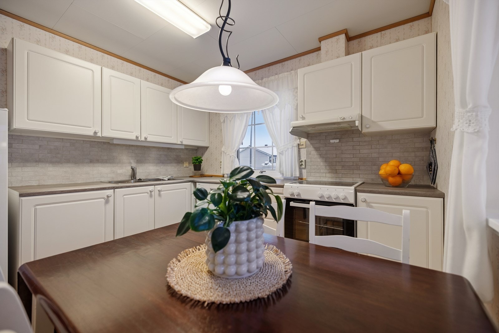 Kjøkkenet har en innredning med hvite, profilerte fronter og laminert benkeplate. Galleribilde