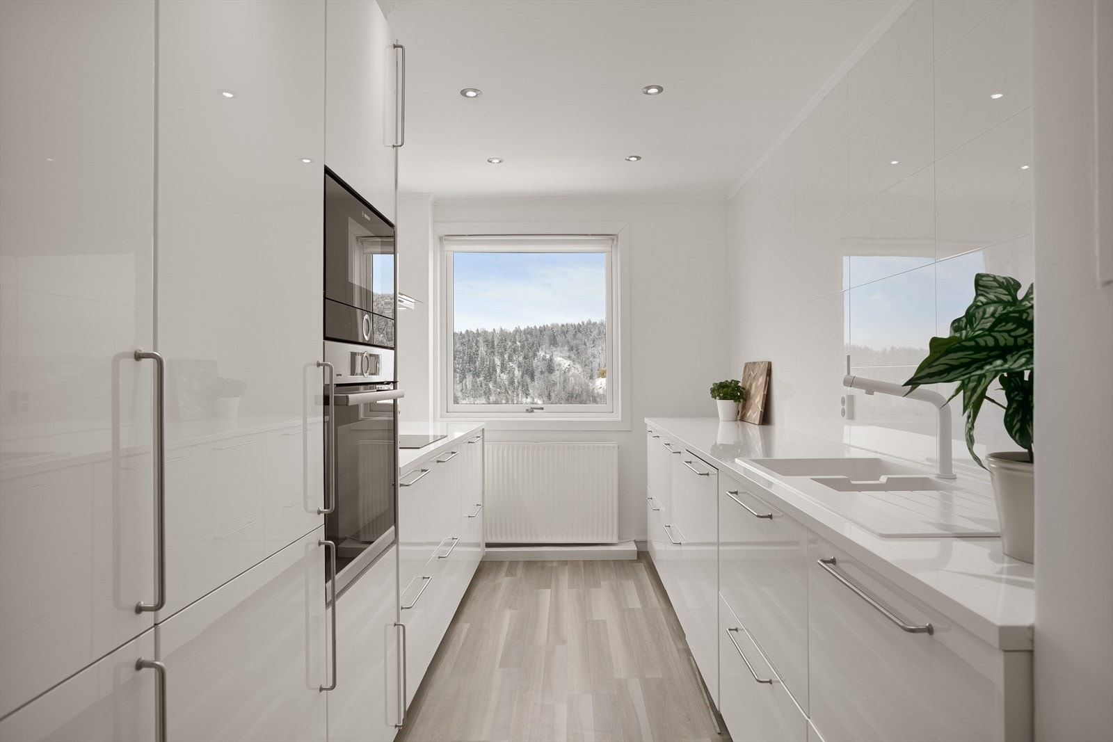 Leiligheten har et praktisk kjøkken med glatte overflater og integrerte hvitevarer Galleribilde