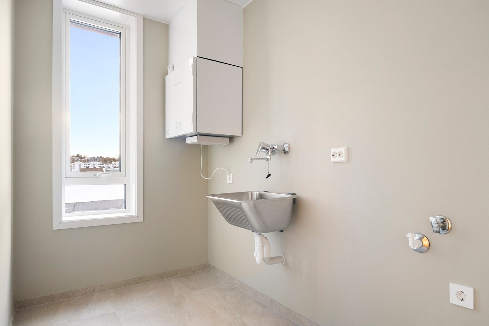 Vaskerommet er av god størrelse, innredet med utslagsvask, opplegg for vaskemaskin og fliser på gulvet. Galleribilde