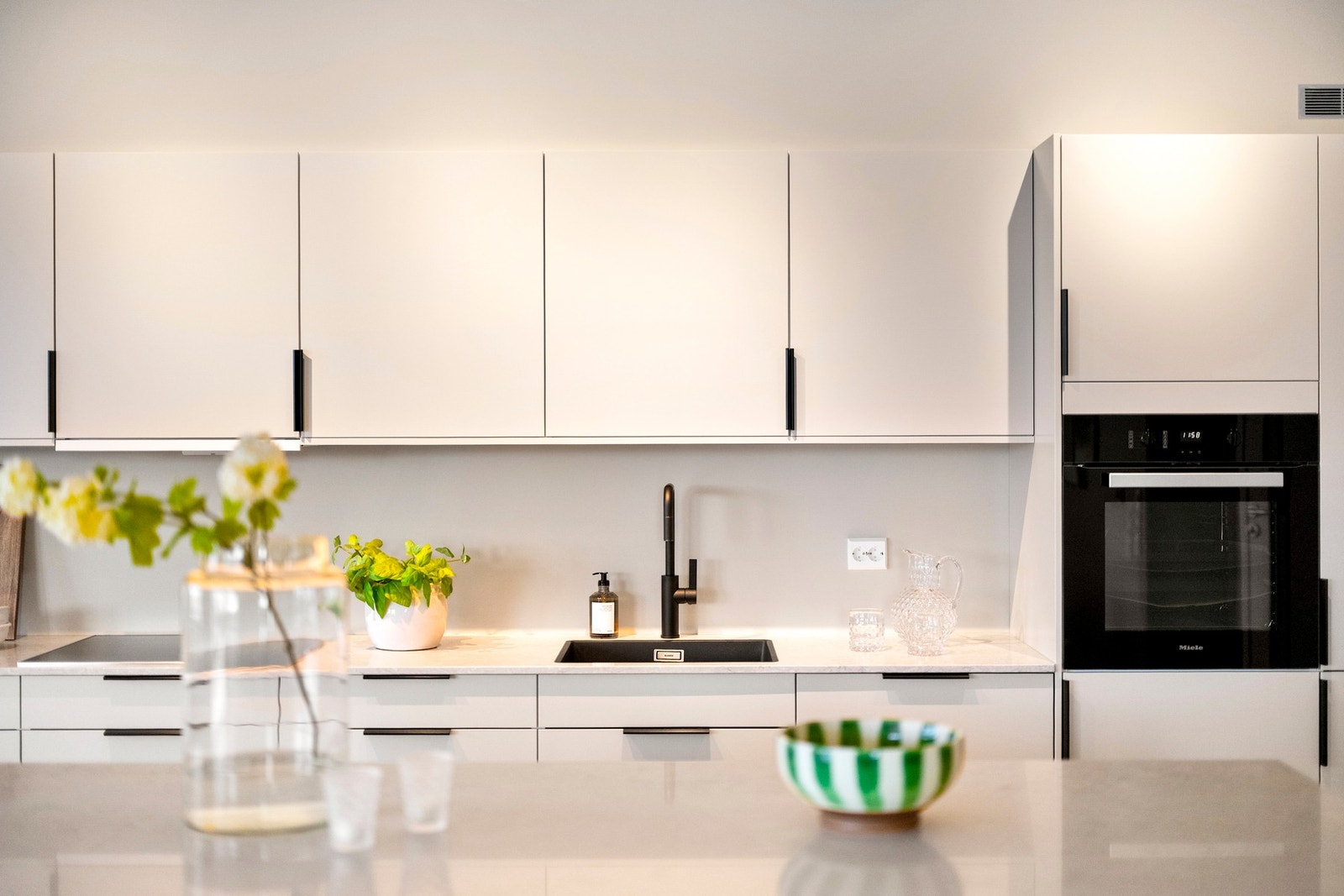 Innredningen fra Sigdal glir sømløst inn, med glatte fronter, nedfelt oppvaskkum og lys benkeplate i marmormønster. Galleribilde