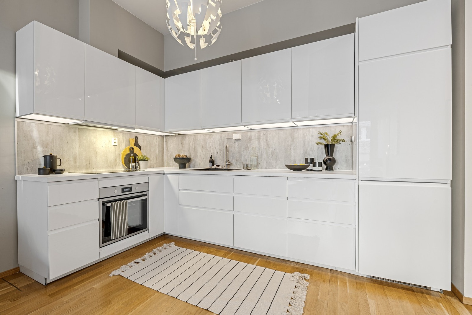 Kjøkkenet fremstår som både lyst og innbydende med bl.a. integrerte hvitevarer, grepsfri innredning og belysning under overskap. Galleribilde