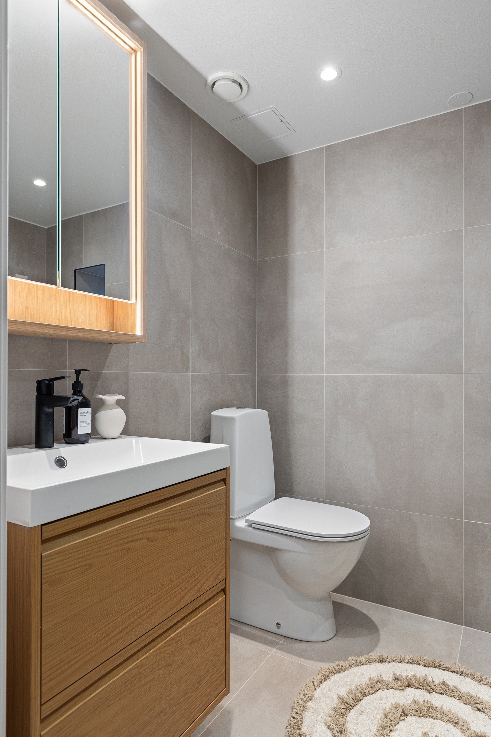 Ny flott baderomsinnredning med skuffer og heldekkende servant, speilskap med integrert belysning over. Baderommet har store flotte fliser på gulv og vegger, deilig gulvvarme og downlights i himlingen. Galleribilde