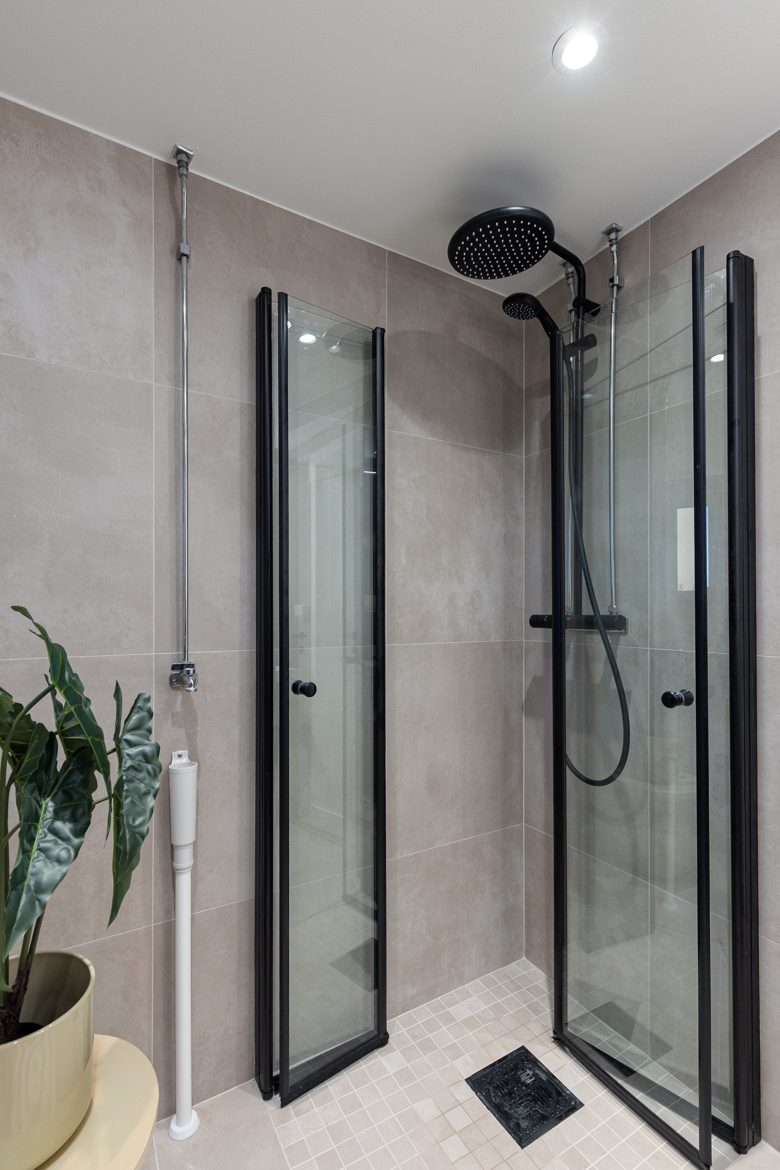 Baderommet er også utstyrt med dusjhjørne med innfellbare glassdører og både hånd- og regnfallsdusj, samt gulvstående toalett. I hjørnet er det plass og opplegg for vaskemaskin. Galleribilde