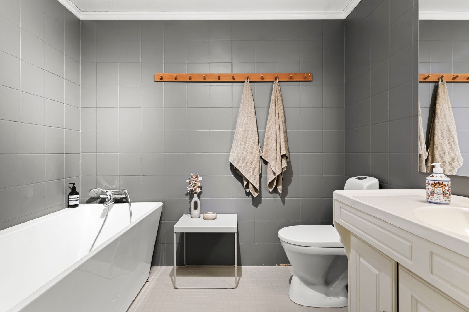 Stort og flislagt bad med behagelig gulvvarme, badekar, servantskap med profilerte fronter, heldekkende servant og gulvmontert toalett. Galleribilde