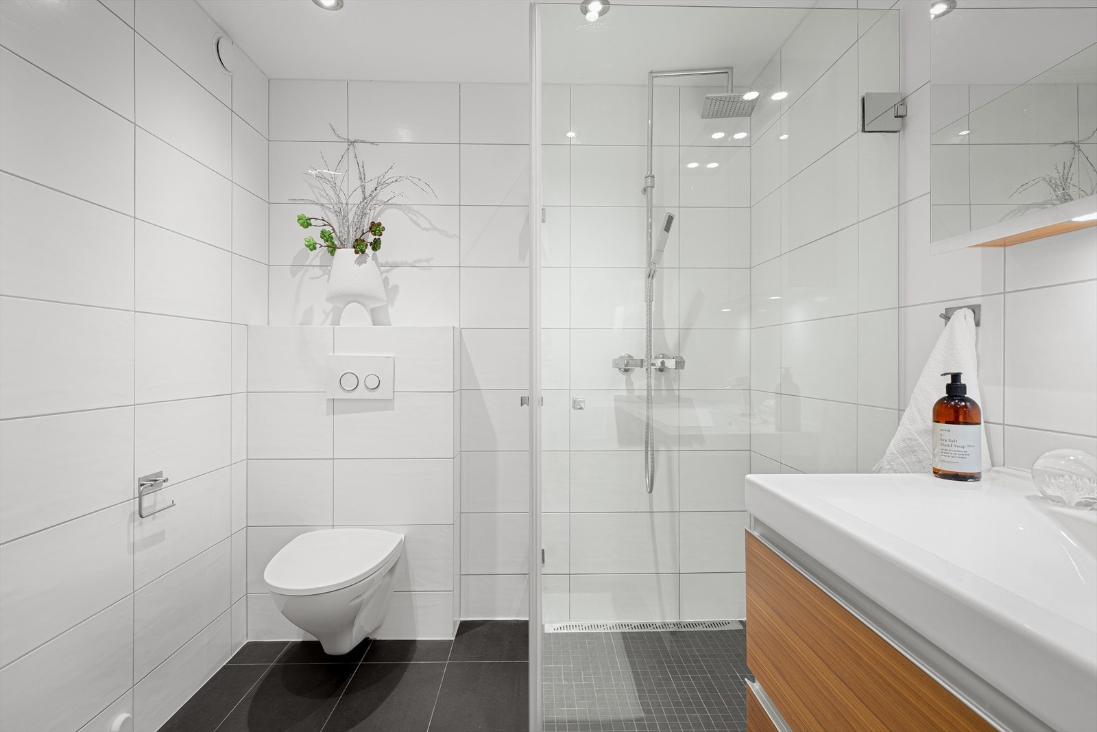 Badet er utstyrt med vegghengt toalett og dusjhjørne med innfellbare glassdører. Galleribilde