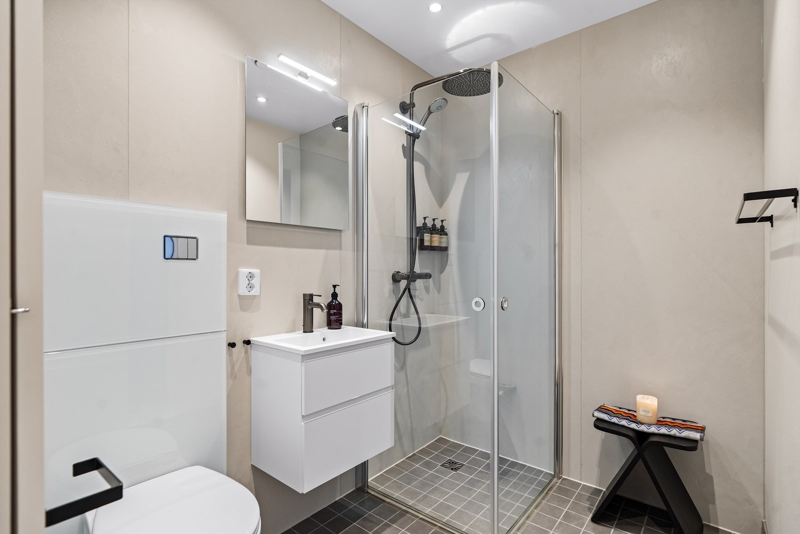 Badet i 1. etasje har et hvitt servantskap med skuffer og et tilhørende speil med eget lys. Et dusjhjørne er utstyrt med stor regnfallsdusj og innfellbare glassdører. Galleribilde