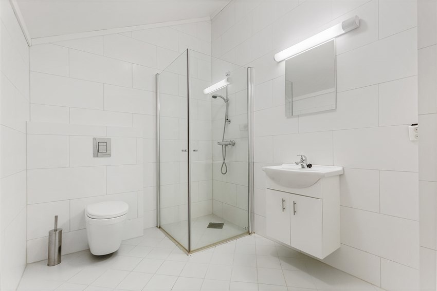 Baderom i praktikantdel - Flislagt med varmekabler, belysning, avtrekk, opplegg for vaskemaskin og tørketrommel. Dusj med innfellbare glassdører, servant med innredning, vegghengt toalett, speil, armatur. Galleribilde