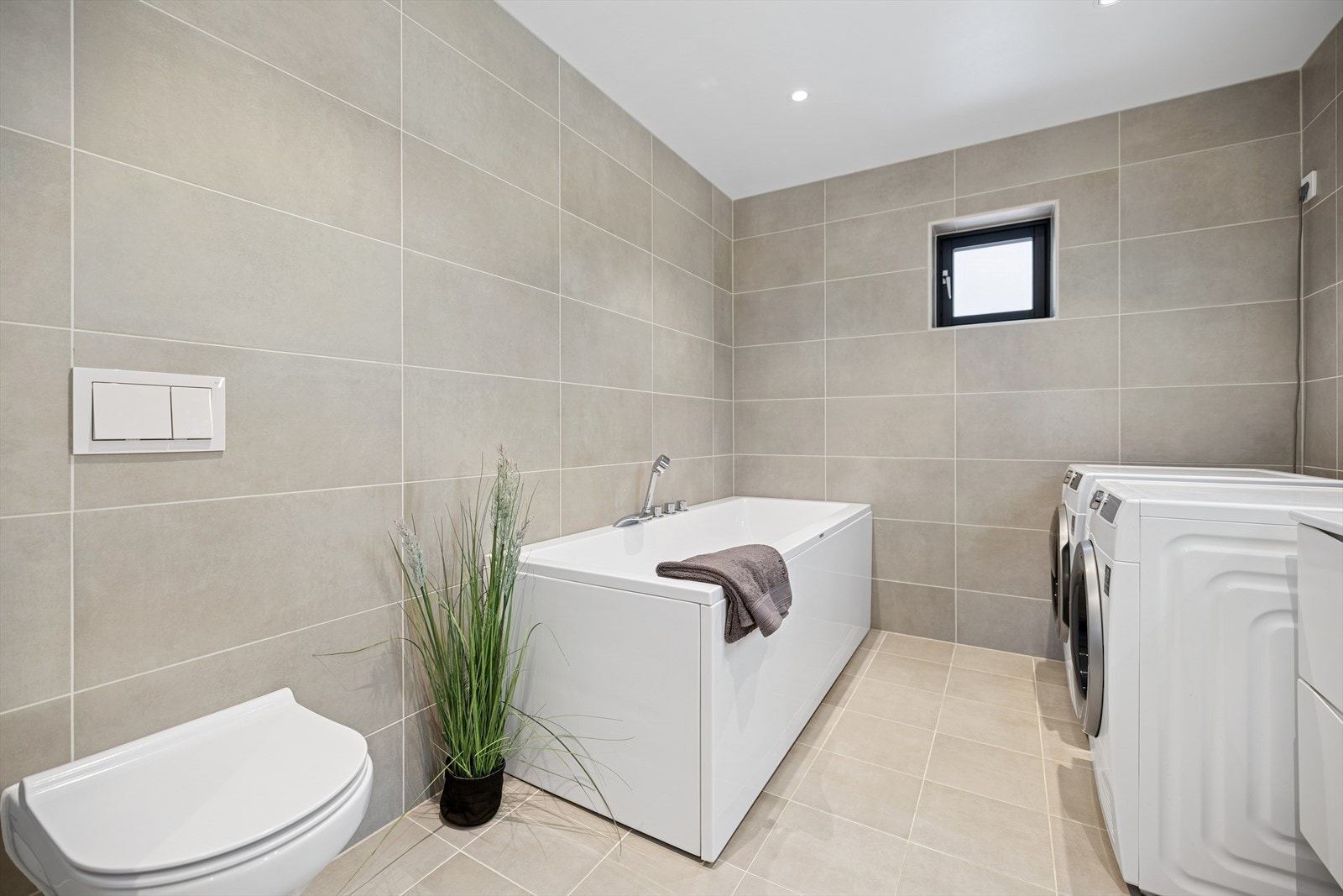 Badet er utstyrt med vegghengt toalett, baderomsinnredning med heldekkende servant, speil med belysning, samt et badekar med termostatstyrt blandebatteri. Galleribilde