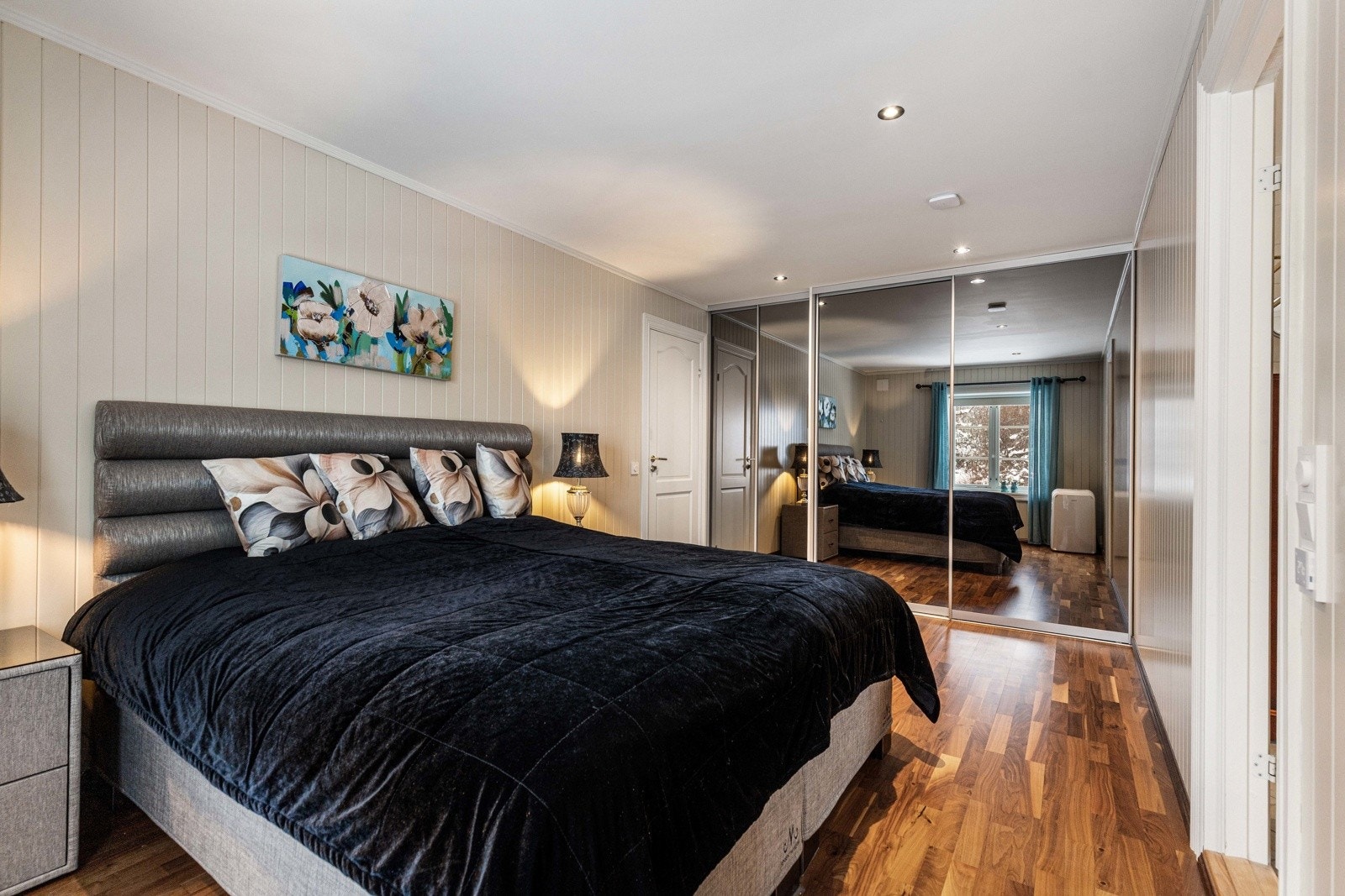 Rommet har god plass til stor dobbeltseng med nattbord på hver side, og er innredet med romslig skyvedørsgarderobe med speilfronter som gir rikelig med oppbevaringsplass. Galleribilde