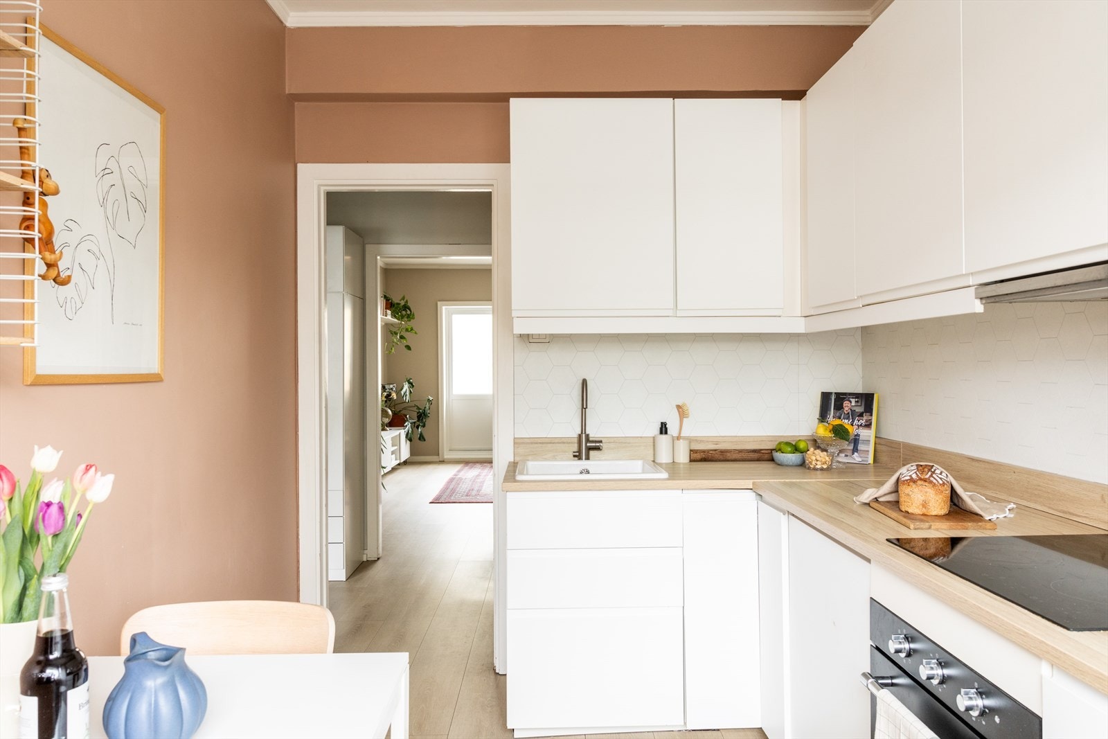 Kjøkkeninnredningen består av lyse, glatte fronter. Benkeplaten er av laminat, og det er montert en plate på veggen over for å fullføre stilen Galleribilde