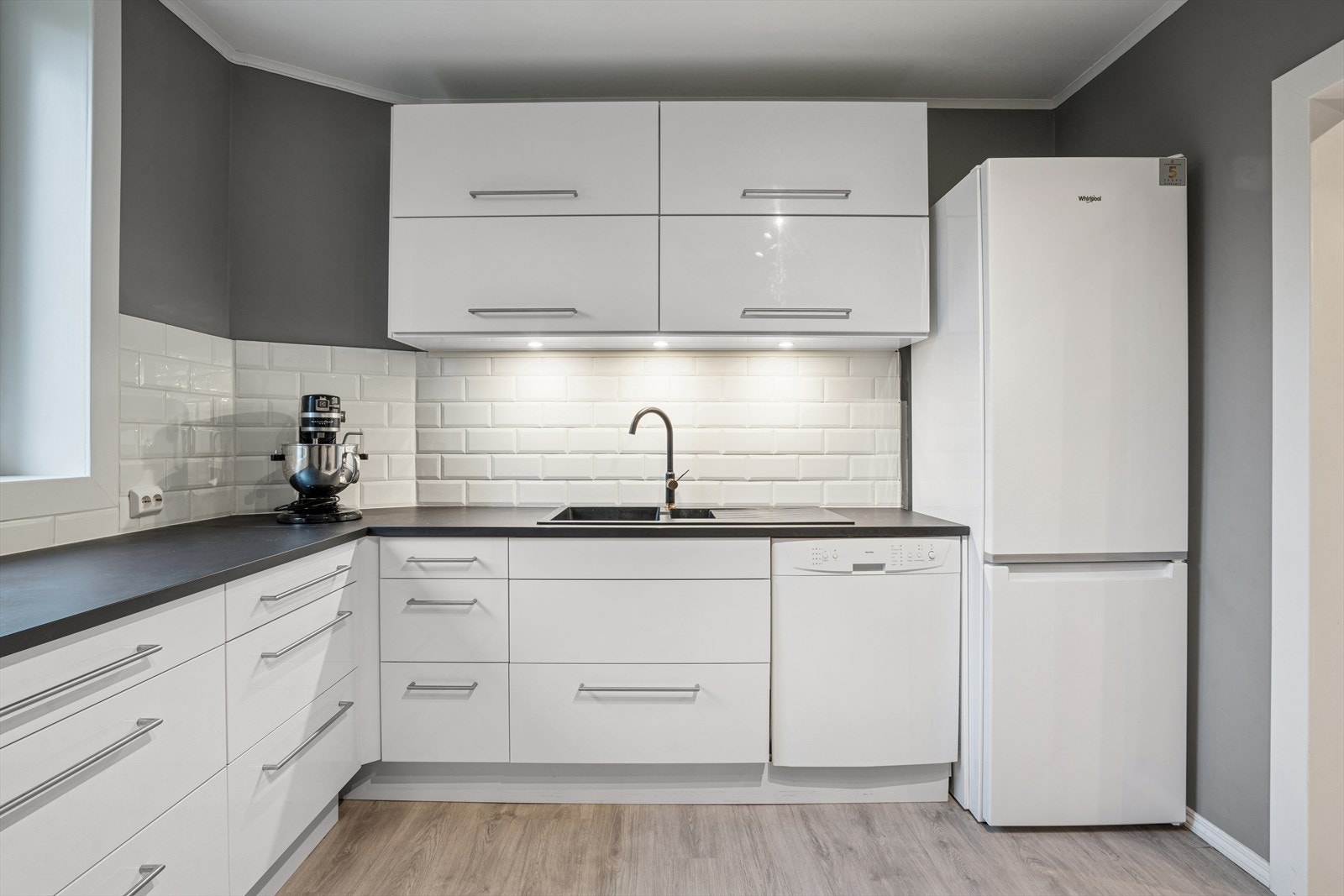 Boligen byr på en tidløs kjøkkeninnredning fra 2020 med under-/overskap, slette fronter, benkeplater av laminat med nedfelt kum i kompositt e.l. og ett-greps blandebatteri. Galleribilde